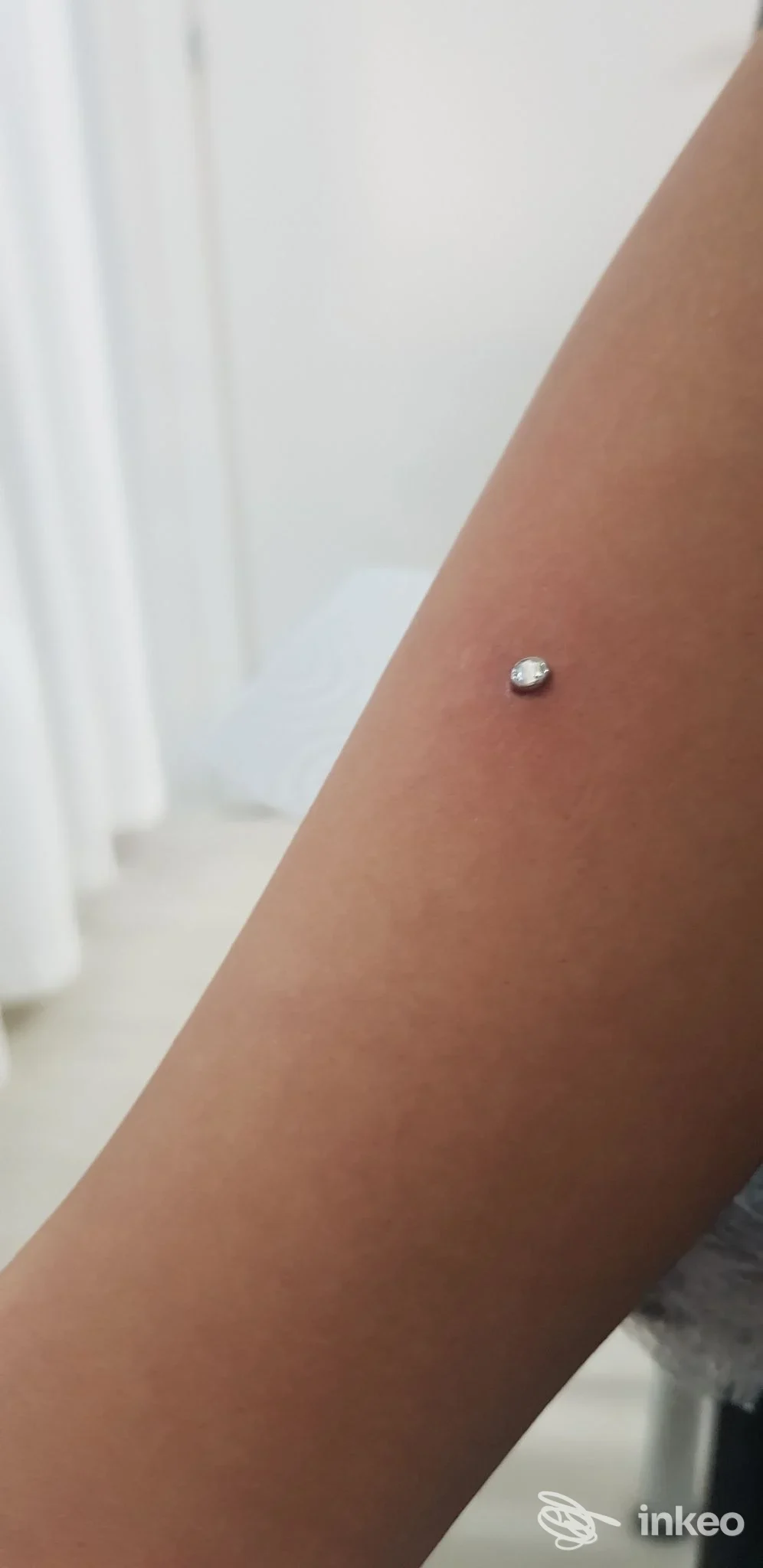 Piercing singolo in metallo visibile sull'avambraccio, scatto ravvicinato. Baruna Piercer, Reggio di Calabria.