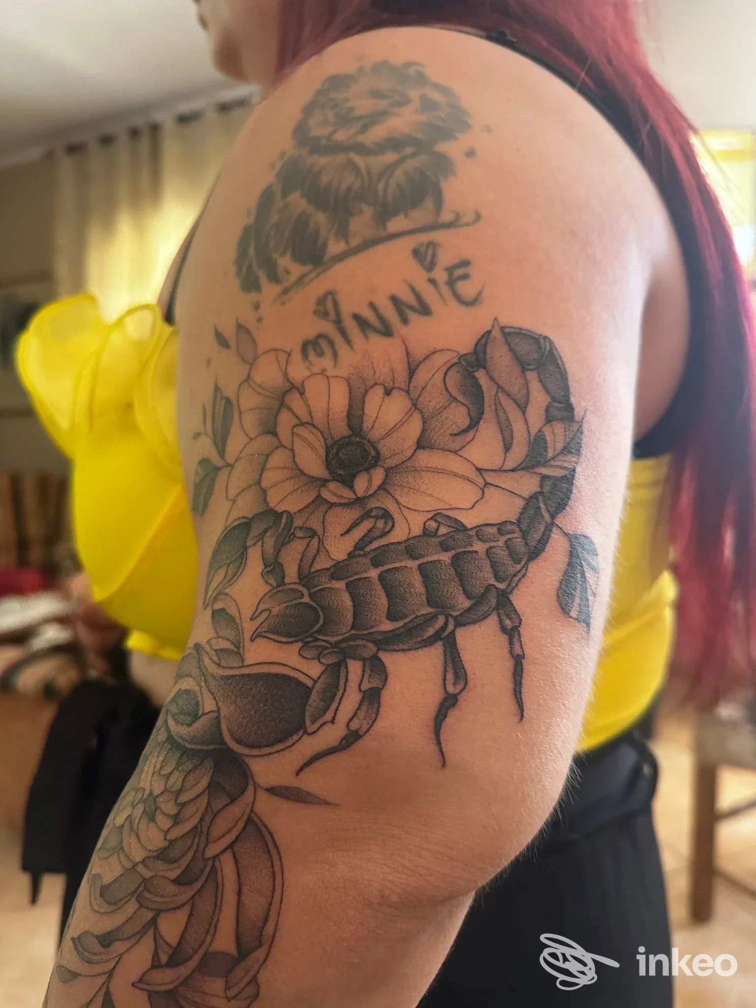 Tattoo visibile sul braccio di una persona: grande motivo floreale in bianco e nero con dettagli, scopaiforme, e una citazione o testo vicino. Studio Sacred Art Tattoo, Lamezia Terme.