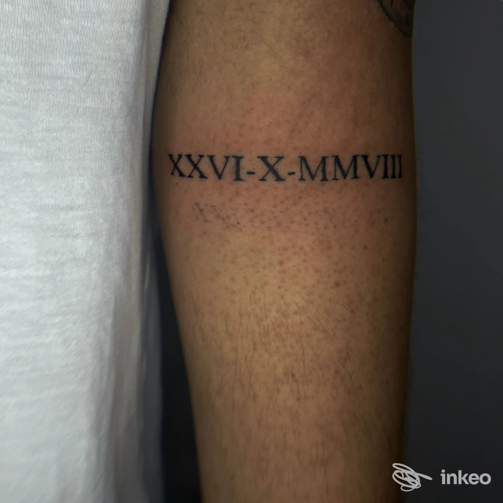 Tatuaggio roman numerale XXVI-X-MMVIII sulla parte interna del braccio, visibile su pelle chiara senza sfondo visivo di altro contenuto.