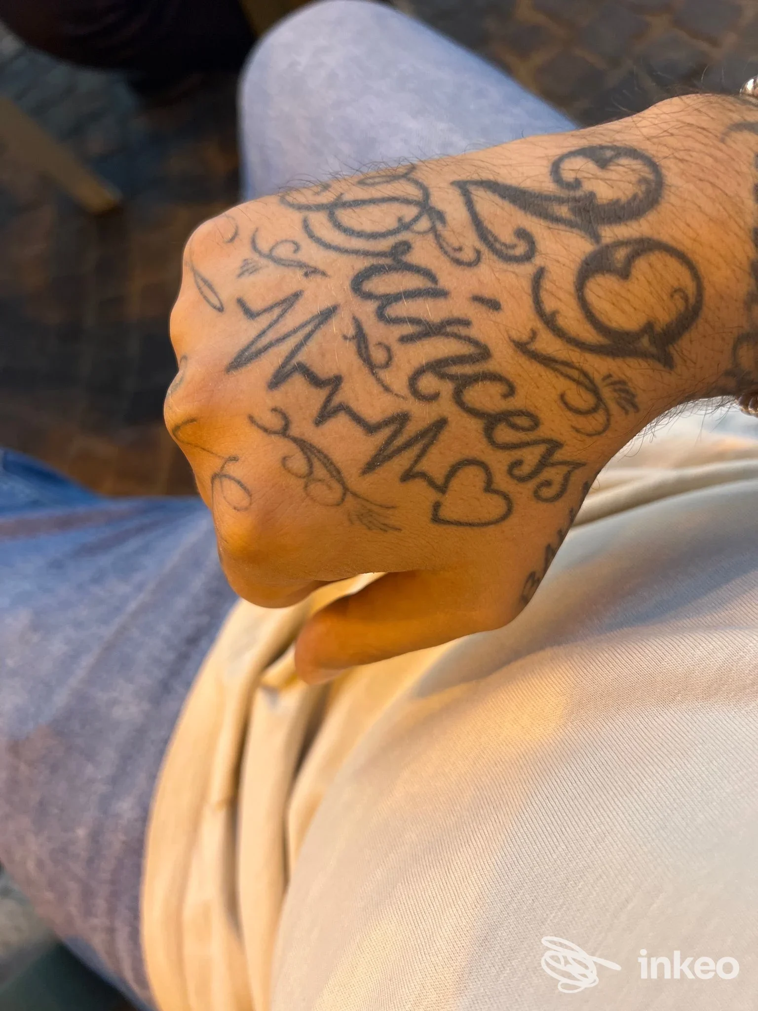 Mano con tatuaggi visibili sulla pelle, scritte e cuori, inquadratura ravvicinata sulla mano; Seven Ink Tattoo Studio, Quattromiglia.