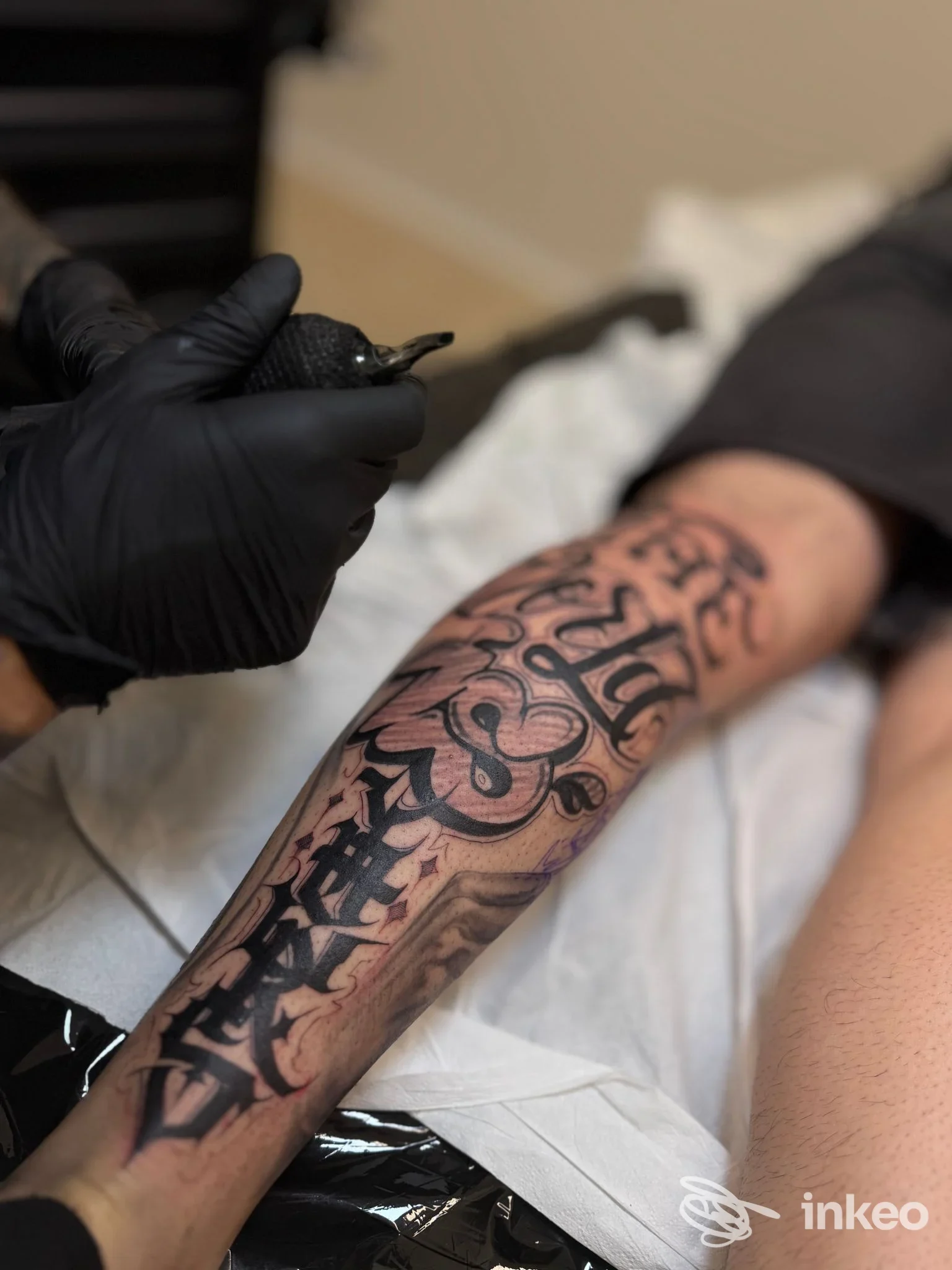 Un braccio di una persona su una tavola da tatuaggio, con un tatuaggio in stile lettering nero molto definito; l’immagine è stata realizzata nel La Tinta Tattoo Studio a Sellia Marina.