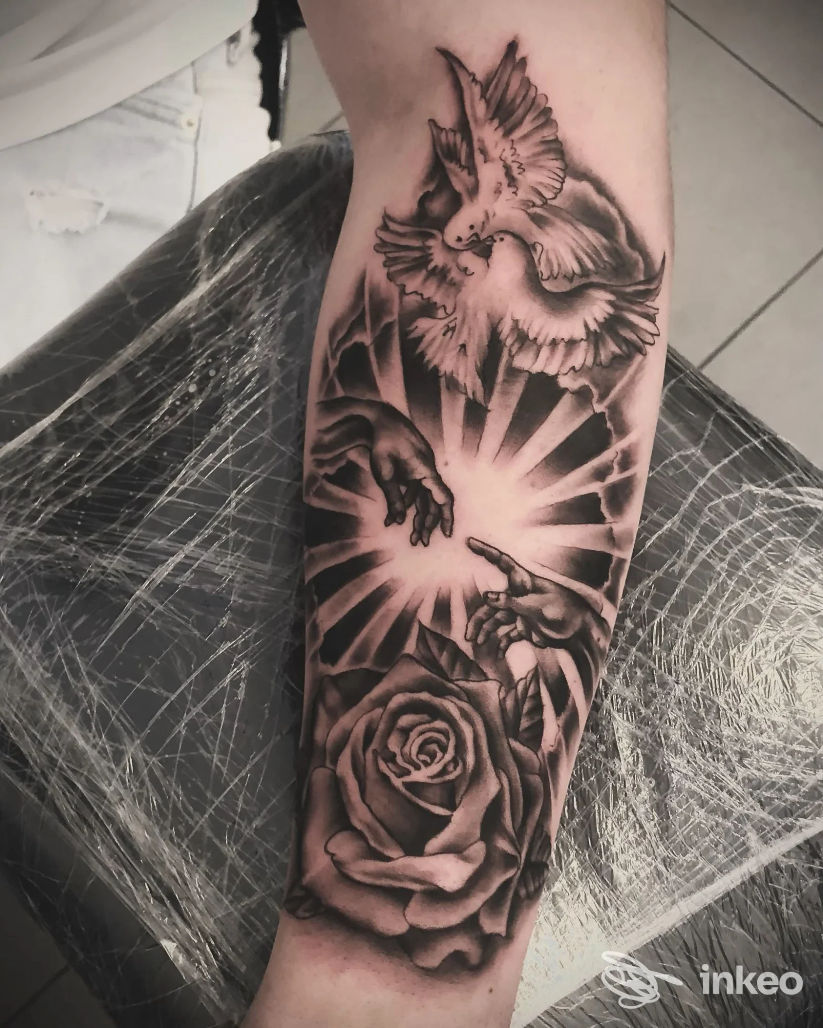 Tatuaggio sul braccio raffigurante una rosa e due colombe in stile realismo, esecuzione nera e grigia su pelle, lavoro di Aldo Gramisci Tattoo a Trebisacce.