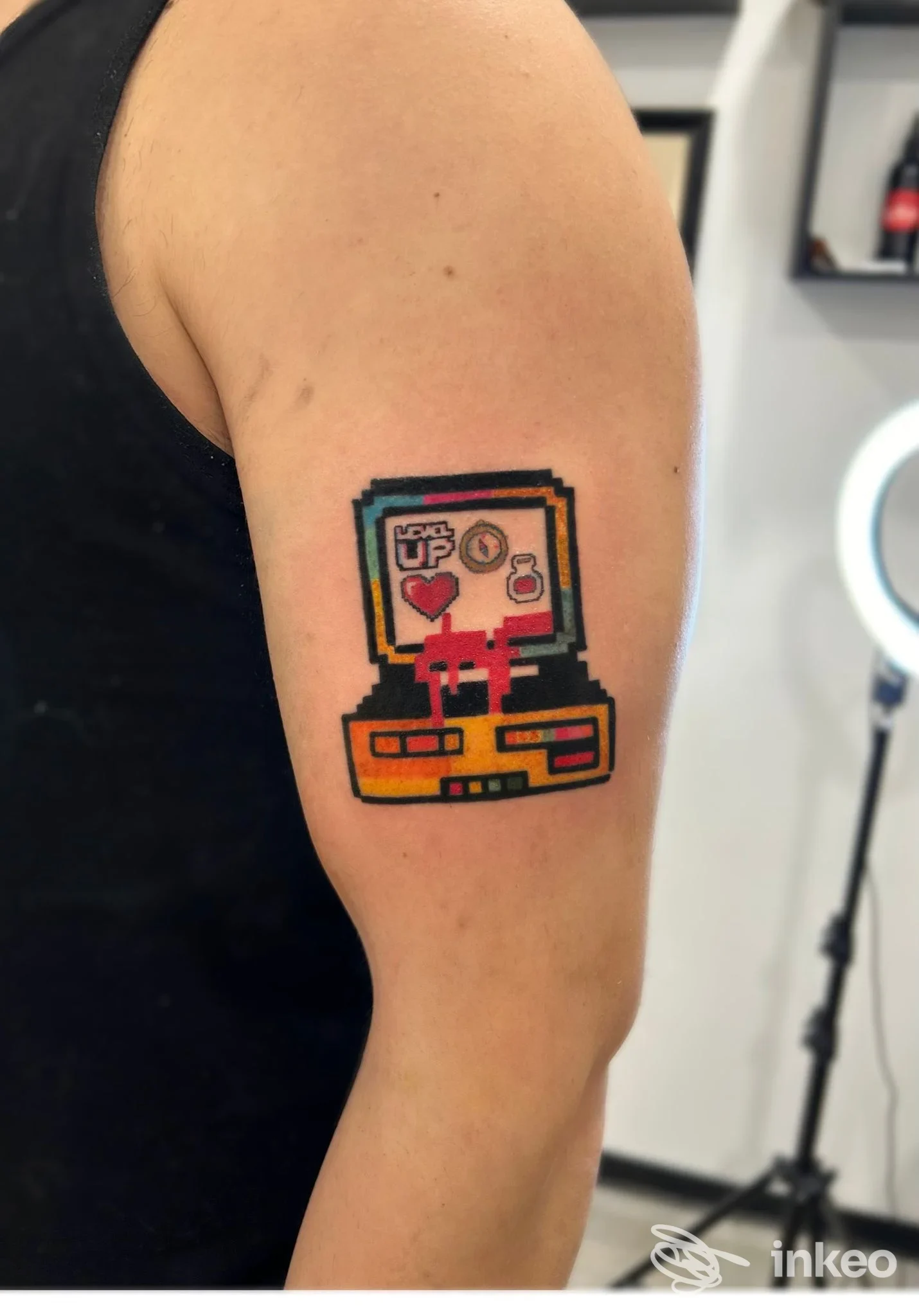 Tattoo in stile pixel art su braccio, raffigurante una console retrò con colori vivaci, realizzata su pelle.