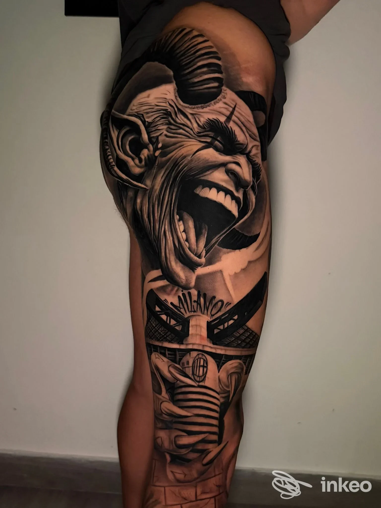 Tattoo sul polpaccio di una persona: scena in bianco e nero/grigio con una testa di scimmia urlante e dettagli decorativi.