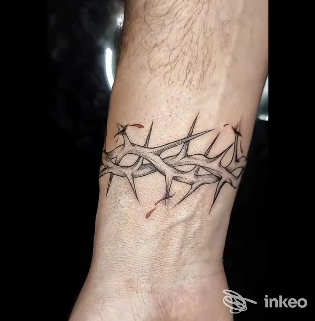 Tatuaggio a cerchio a spine sul polso, realizzato sulla pelle, linee nere definite con riflessi e piccoli dettagli color carne.