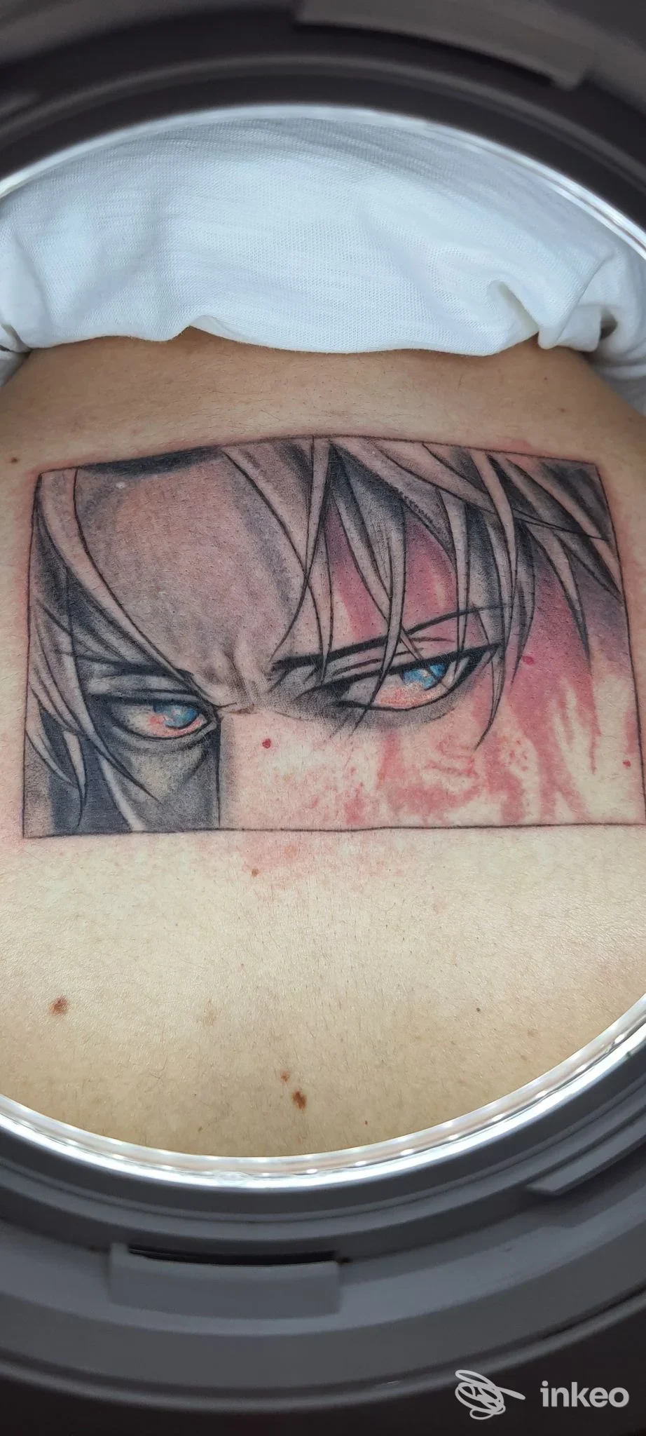 Tatuaggio visibile sulla pelle raffigurante occhi stilizzati in stile anime, con tonalità scure e rosse sfumature sul braccio, realizza un ritratto netto e definito.