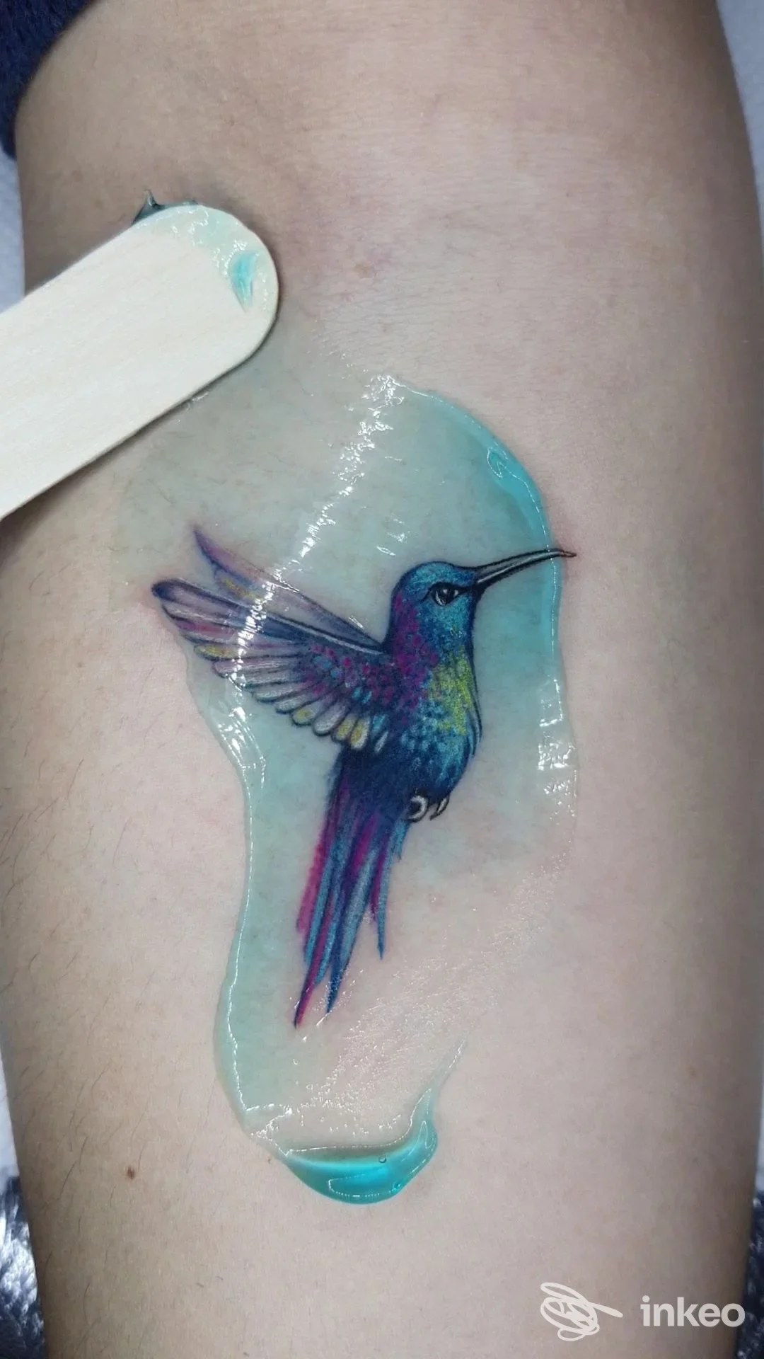 Tatuaggio realistico di colibrì colorato realizzato sulla pelle del braccio, visibile in primo piano con sfondo neutro, eseguito nello studio Onmyskin_tattoo a Polistena.