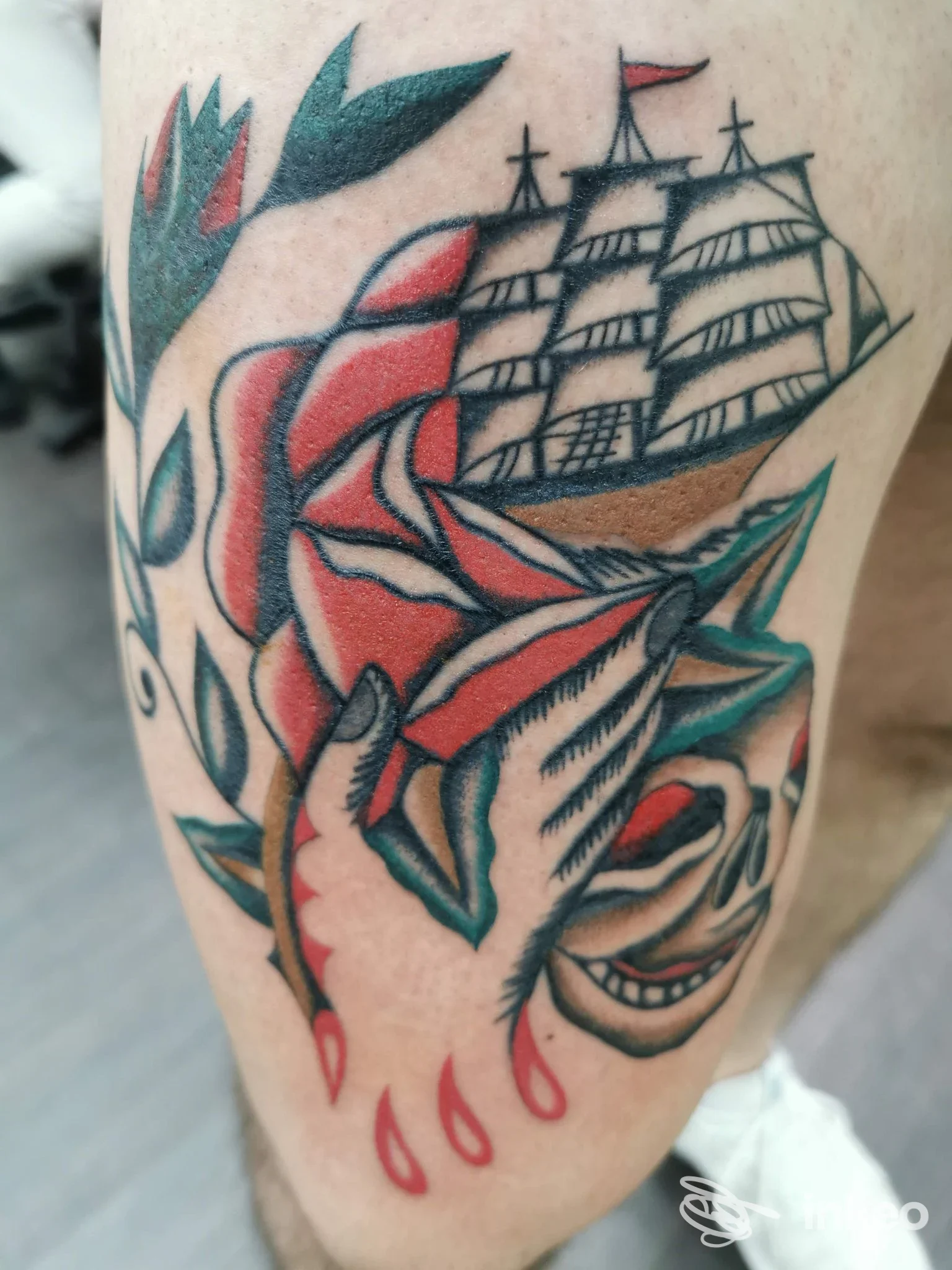 Tatuaggio visibile su pelle raffigurante una nave a due o tre alberi e una rosa rossa con mani di fronte, colore vivace. Studio Dragonfly Tattoo, Reggio di Calabria.
