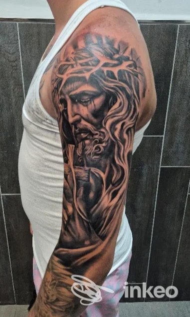 Tattoo sul braccio di una persona, raffigurante una figura umana stilizzata, visibile sul bianco della maglia; studio Kalabria Ink Le Castella, Le Castella, evidente senza overlay o immagine di schermo.