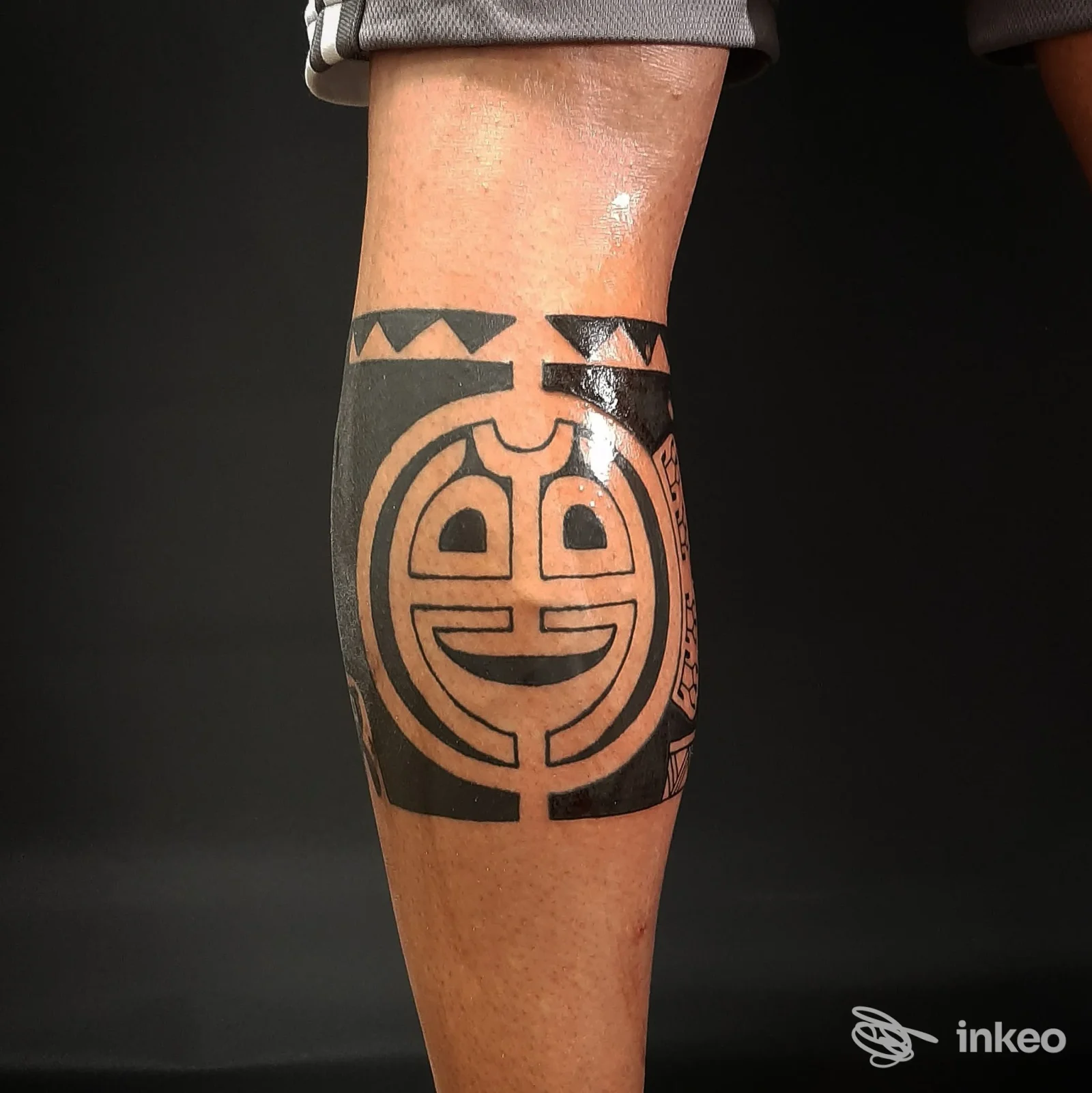 Tatuaggio geometrico nero su polpaccio: disegno circolare con linee spesse su pelle reale, situazione di studio a Reggio Calabria.