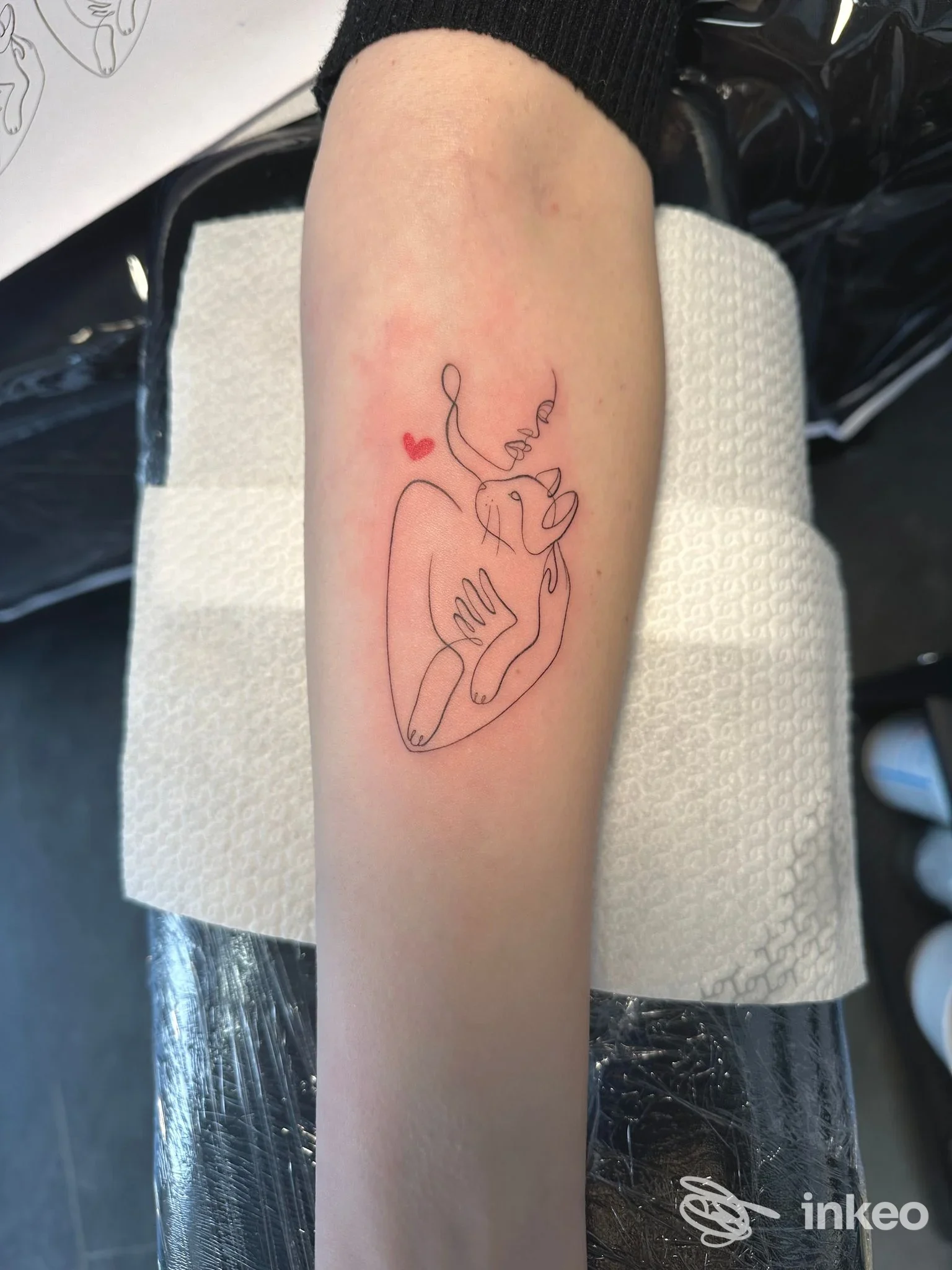 Tattoo lineare su avambraccio: disegno nero con piccoli cuori rossi.