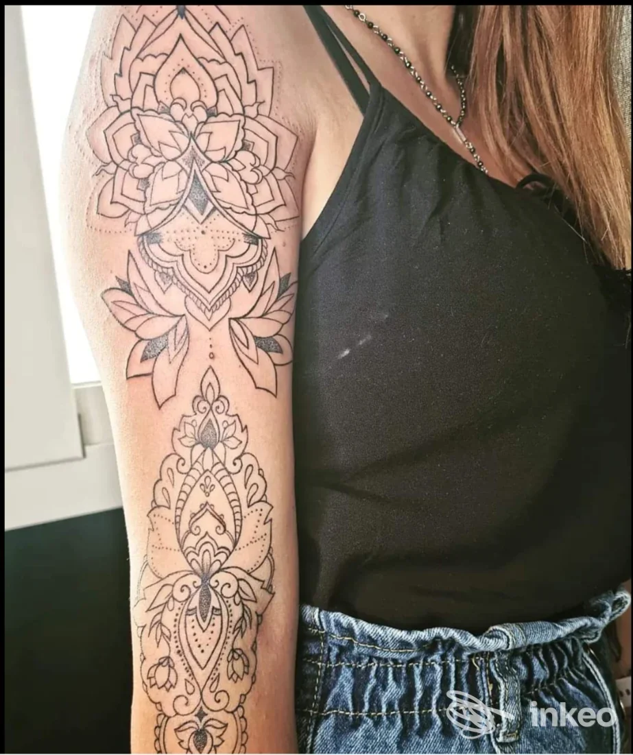 Tatuaggio visibile sul braccio di una persona: motivo geometrico/mandala ben definito, eseguito sulla pelle, con abbigliamento casual e sfondo neutro; studio Rebelmuse Tattoo, Montepaone.