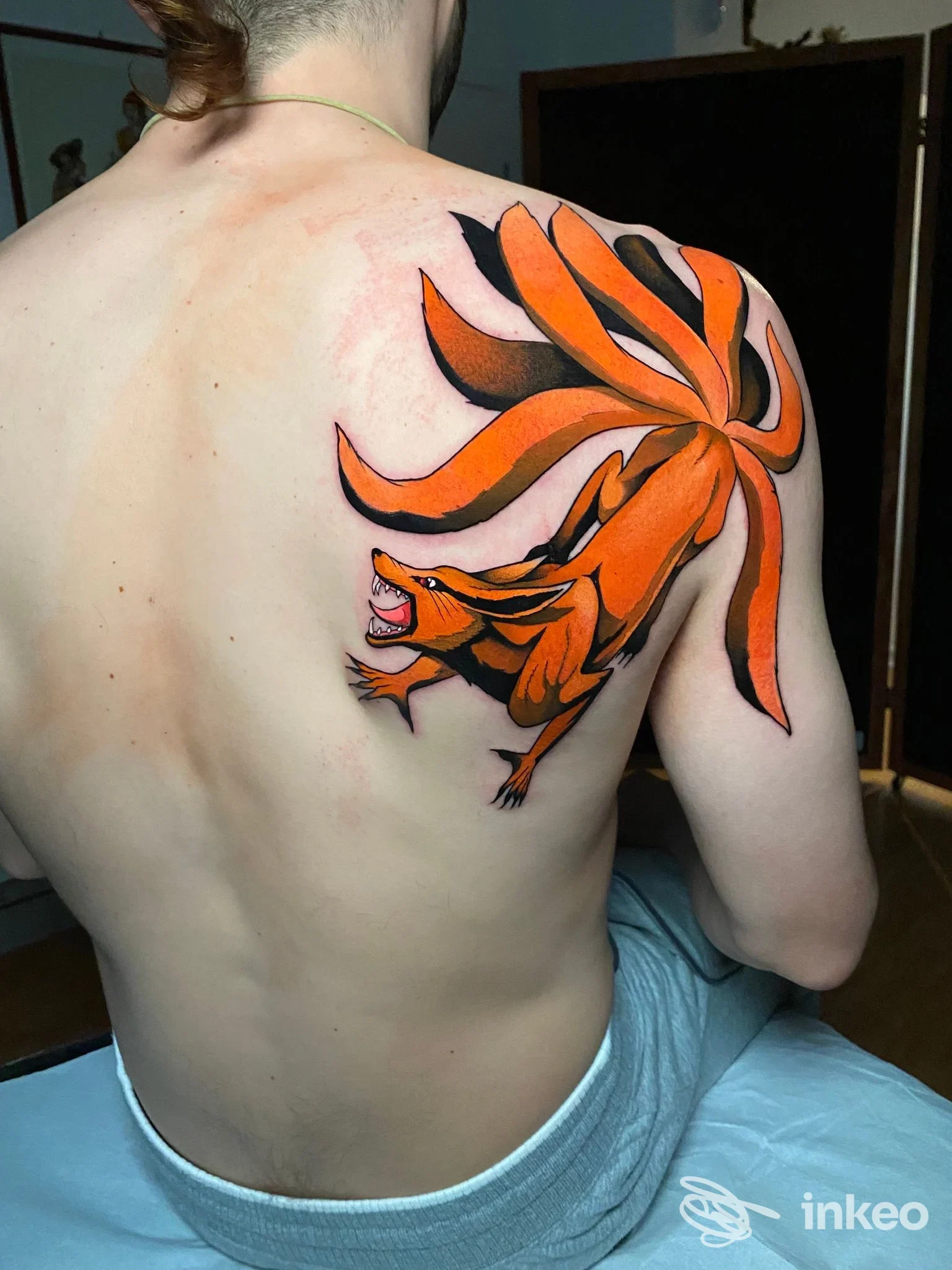 Schiena di persona nuda con tatuaggio ornato di tigre e coda arancione, realizzato in stile neotraditional/giapponese, visibile sul lato sinistro della schiena.