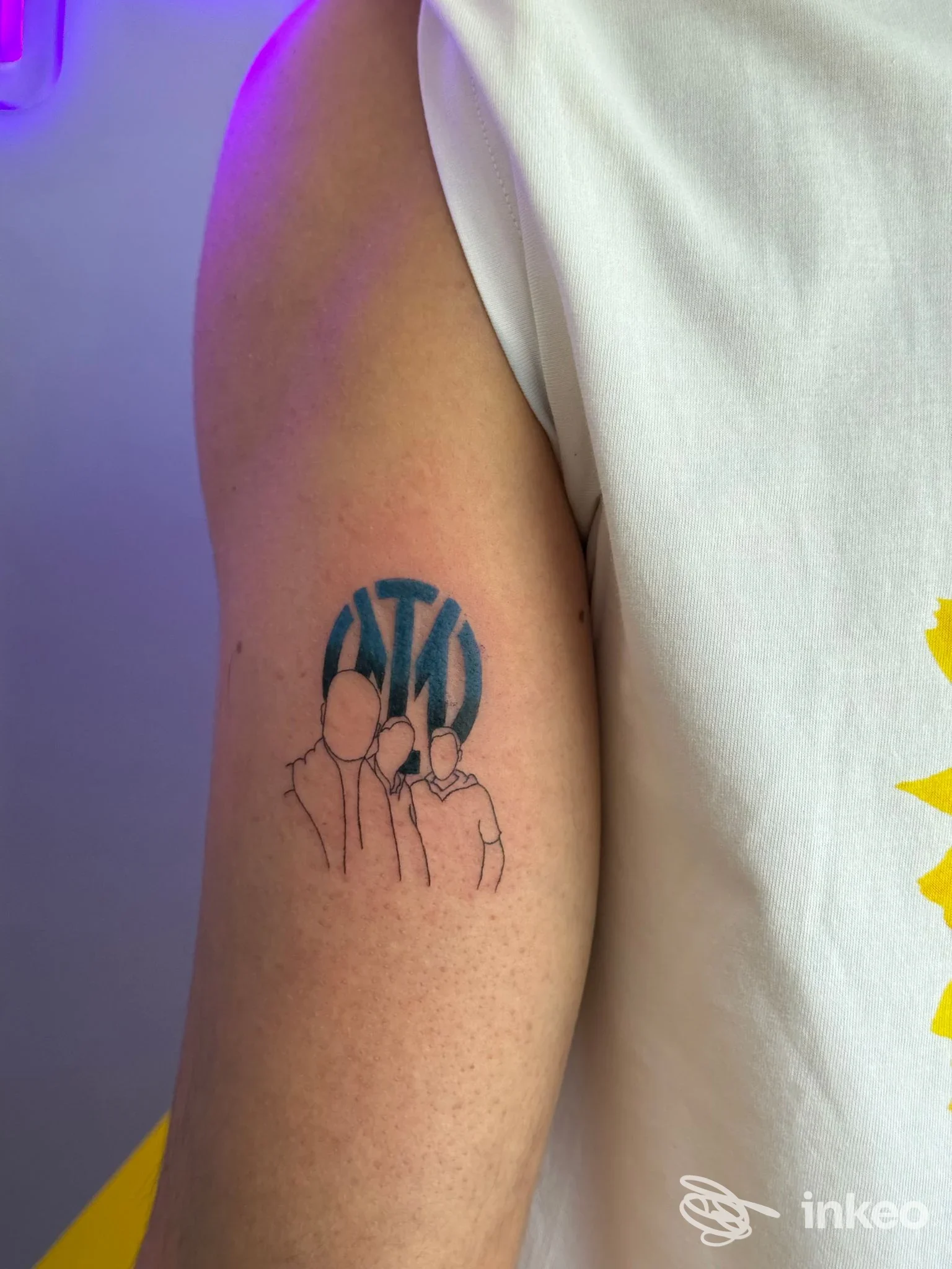 Tattoo su braccio con disegno stilizzato di tre persone, contorno sottile in nero/blu su pelle chiara, senza volto interamente visibile.