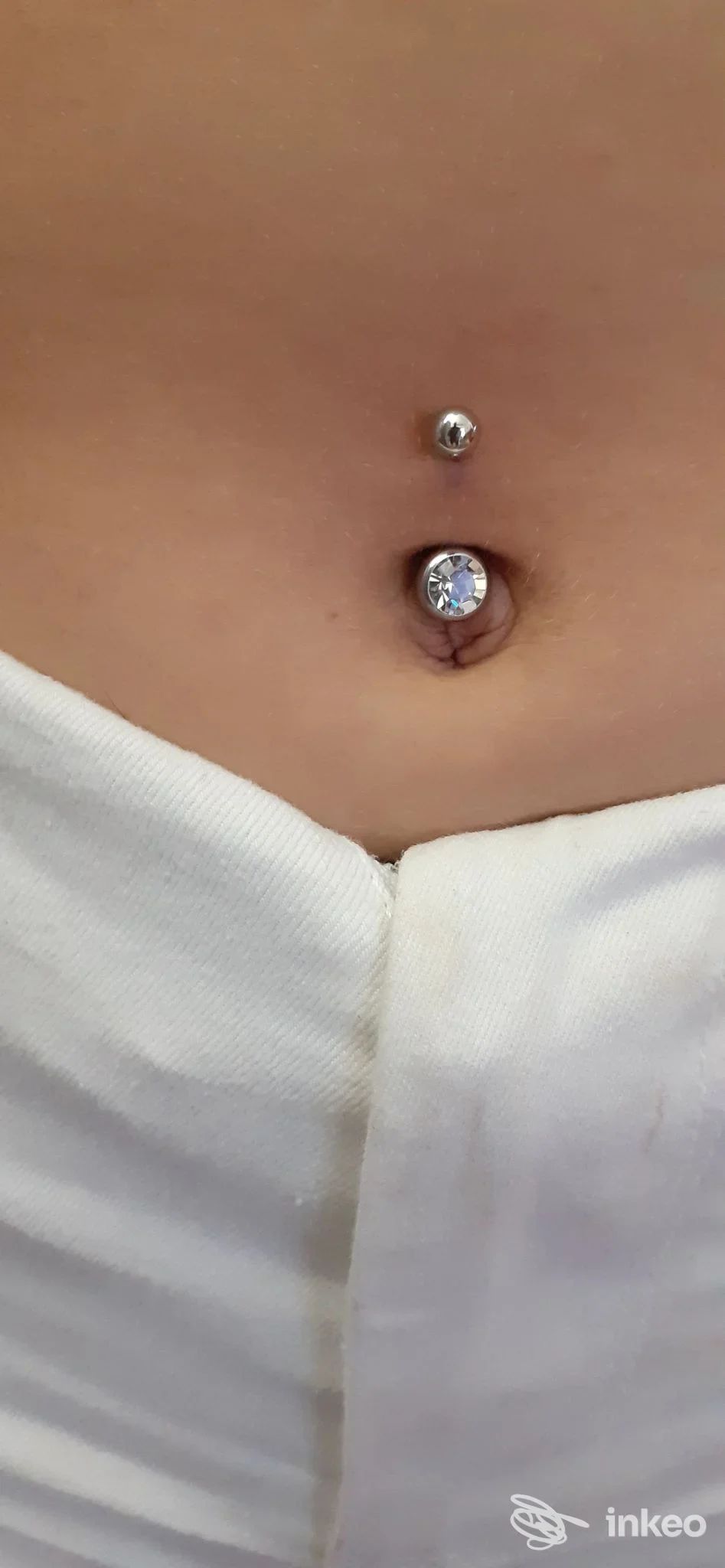 Pancia nuda con due piercing sull'addome, uno all'ombelico con gemma grande e uno sopra, a pochi centimetri. Indispensabile la chiara visibilità del corpo.