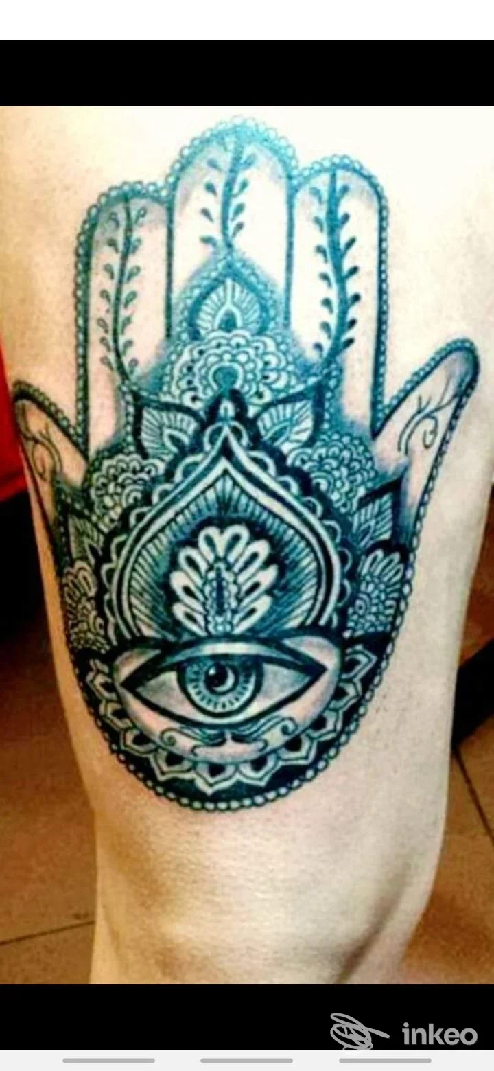 Tattoo a mano Hamsa con occhio al centro, disegno in blu/nero su pelle reale, visibile sul polpaccio o gamba.