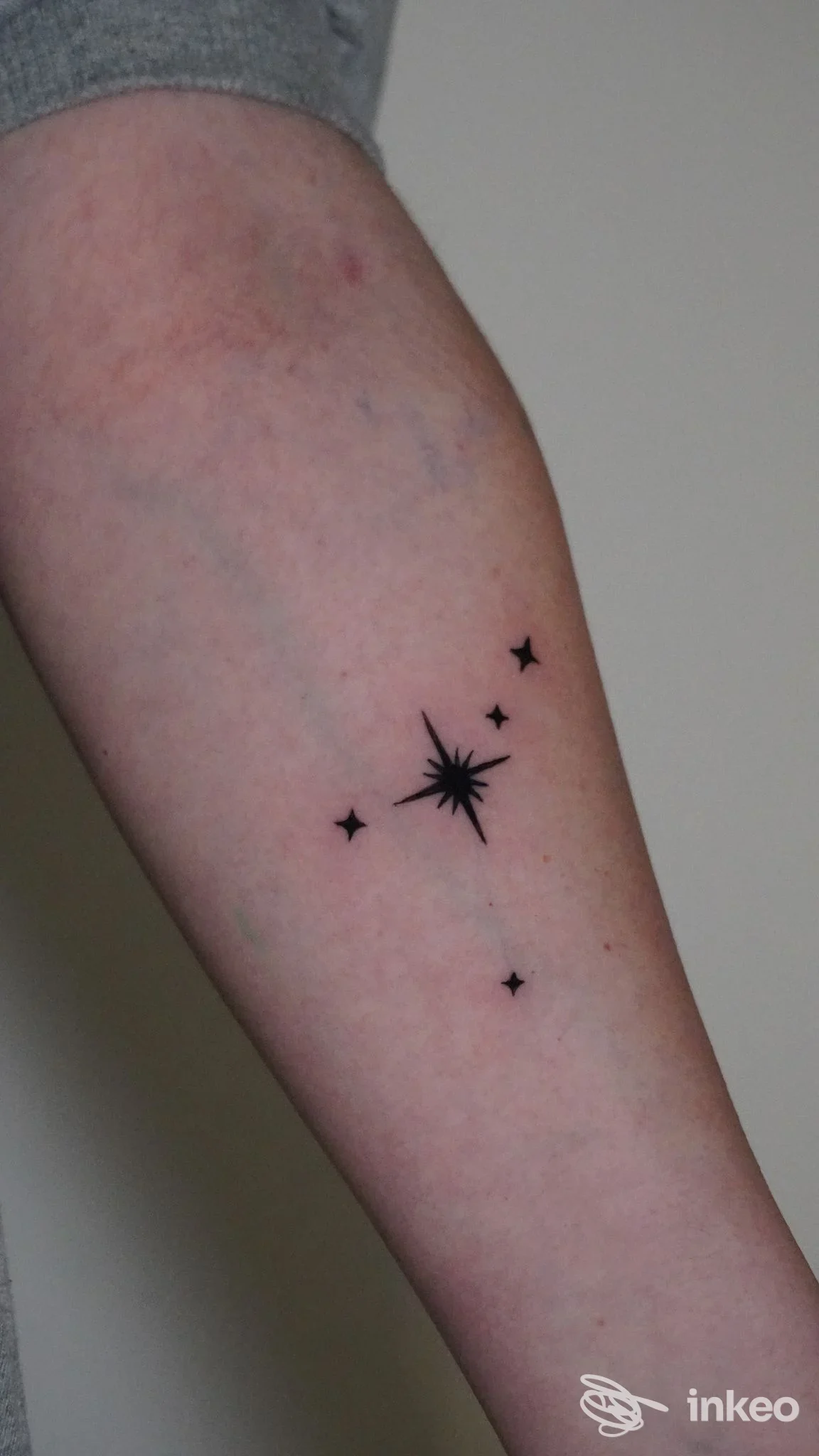 Avambraccio di persona con tatuaggio a tema costellazione, disegno nero di stelle situato sulla parte esterna dell’avambraccio.