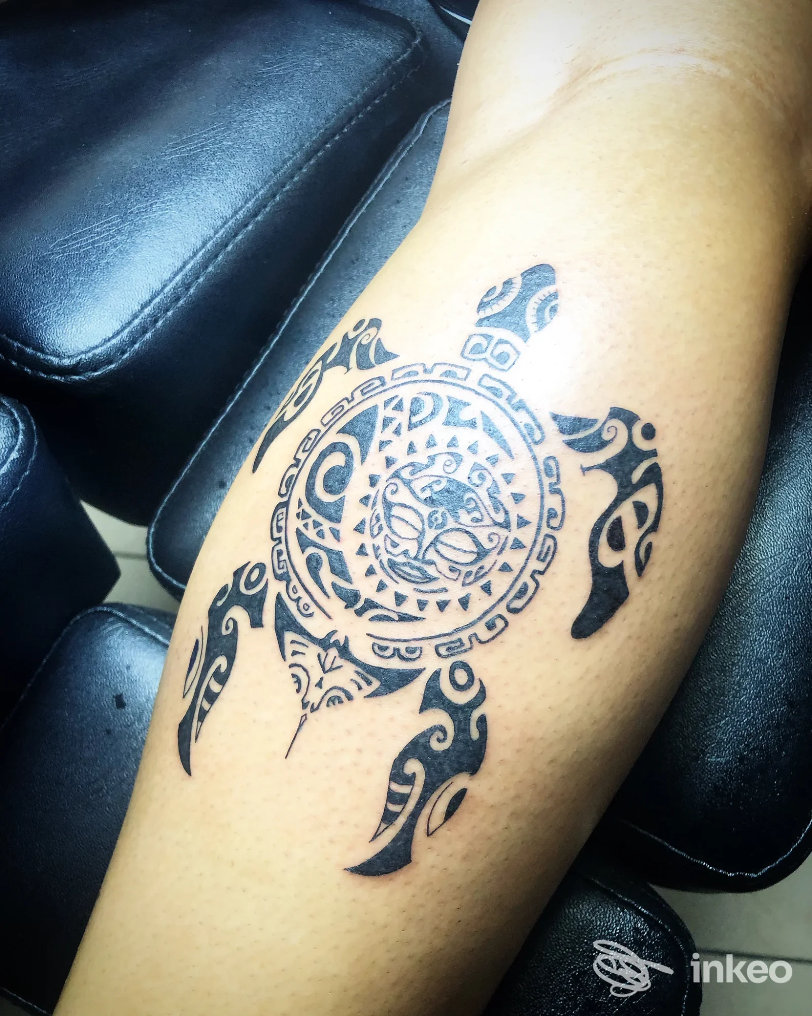 Tattoo circolare geometrico-tribale nero su braccio, con dettagli Ankh-like, esecuzione su pelle chiara.