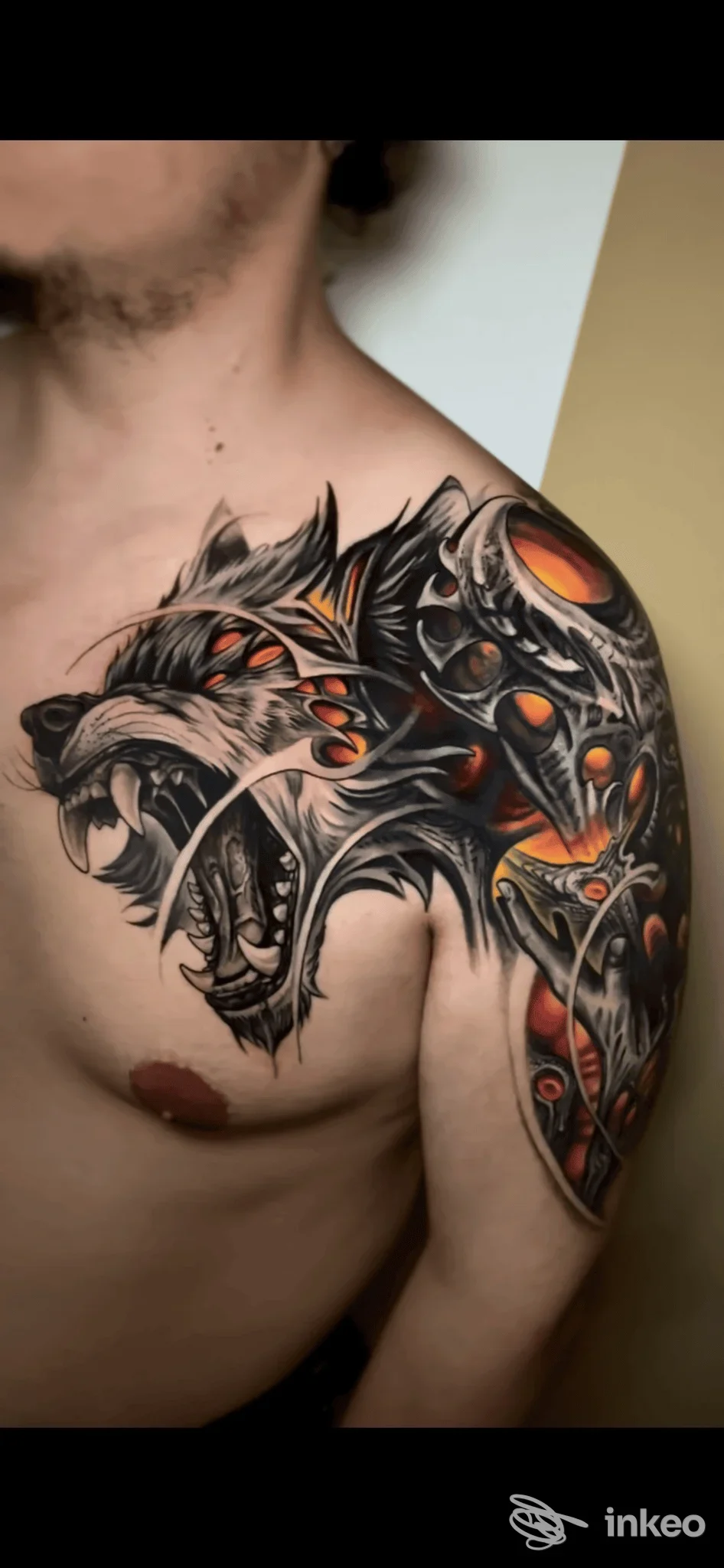 Tattoo a tema animale su spalla e petto di un uomo, stile dark neo-tradizionale con linee nere e rossi arancioni, visibile direttamente sulla pelle.