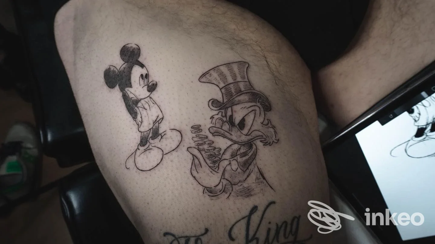 Tattoo su braccio raffigurante Mickey Mouse e un personaggio con cappello, eseguito presso Hollywood Tattoo a Reggio Calabria, inchiostro nero.