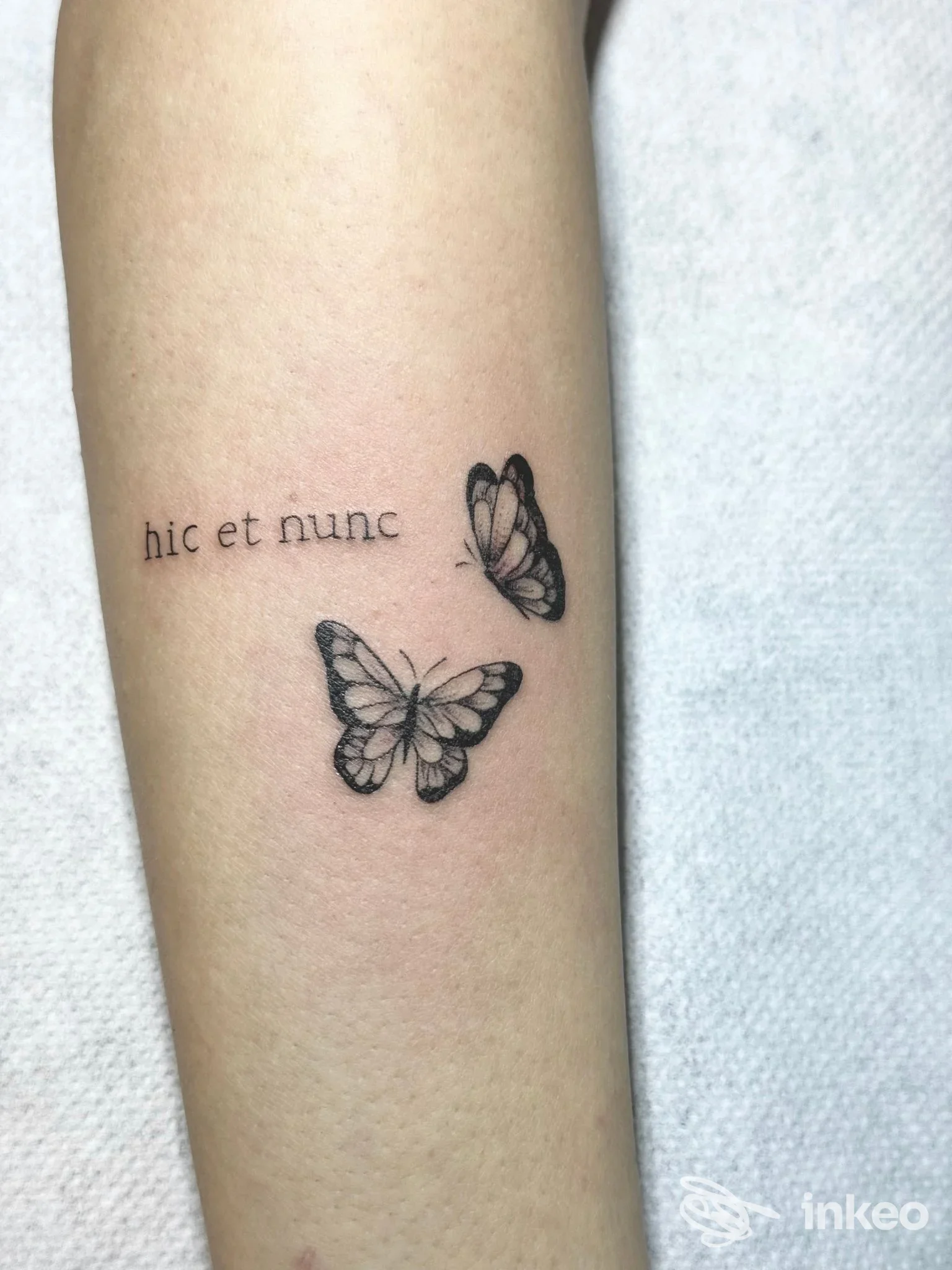 Tattoo su pelle raffigurante due farfalle in nero e la frase latina "hic et nunc" sul braccio, realizzato da Fabink Tattoo a Cosenza.