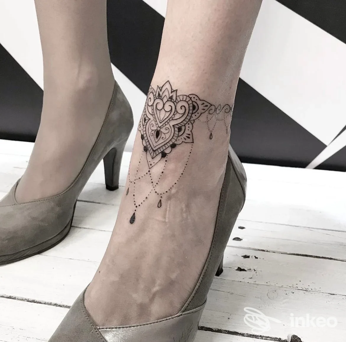Tatuaggio decorativo a cuore mandala sull'osso della caviglia, visibile su piede con décolleté e scarpa, senza volto visibile.