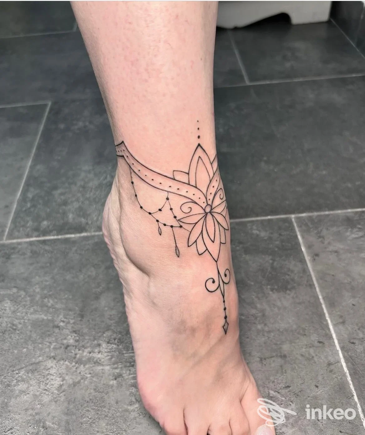 Tatuaggio in stile floreale mandala visibile sulla caviglia/piede destro, monocolore nero, realizzato direttamente sulla pelle.