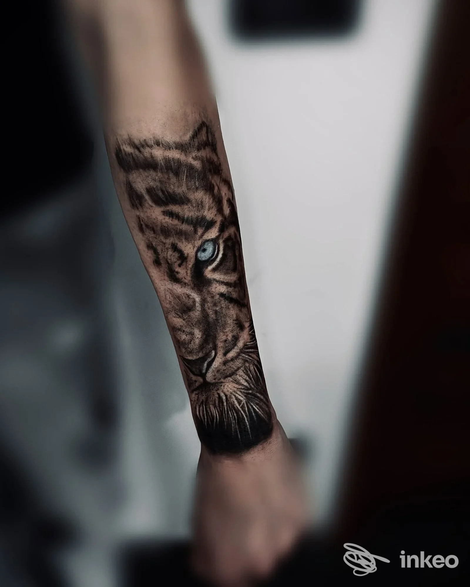 Tattoo realistico di una tigre sulla porzione inferiore dell'avambraccio sinistro, visibile parte della mano.
