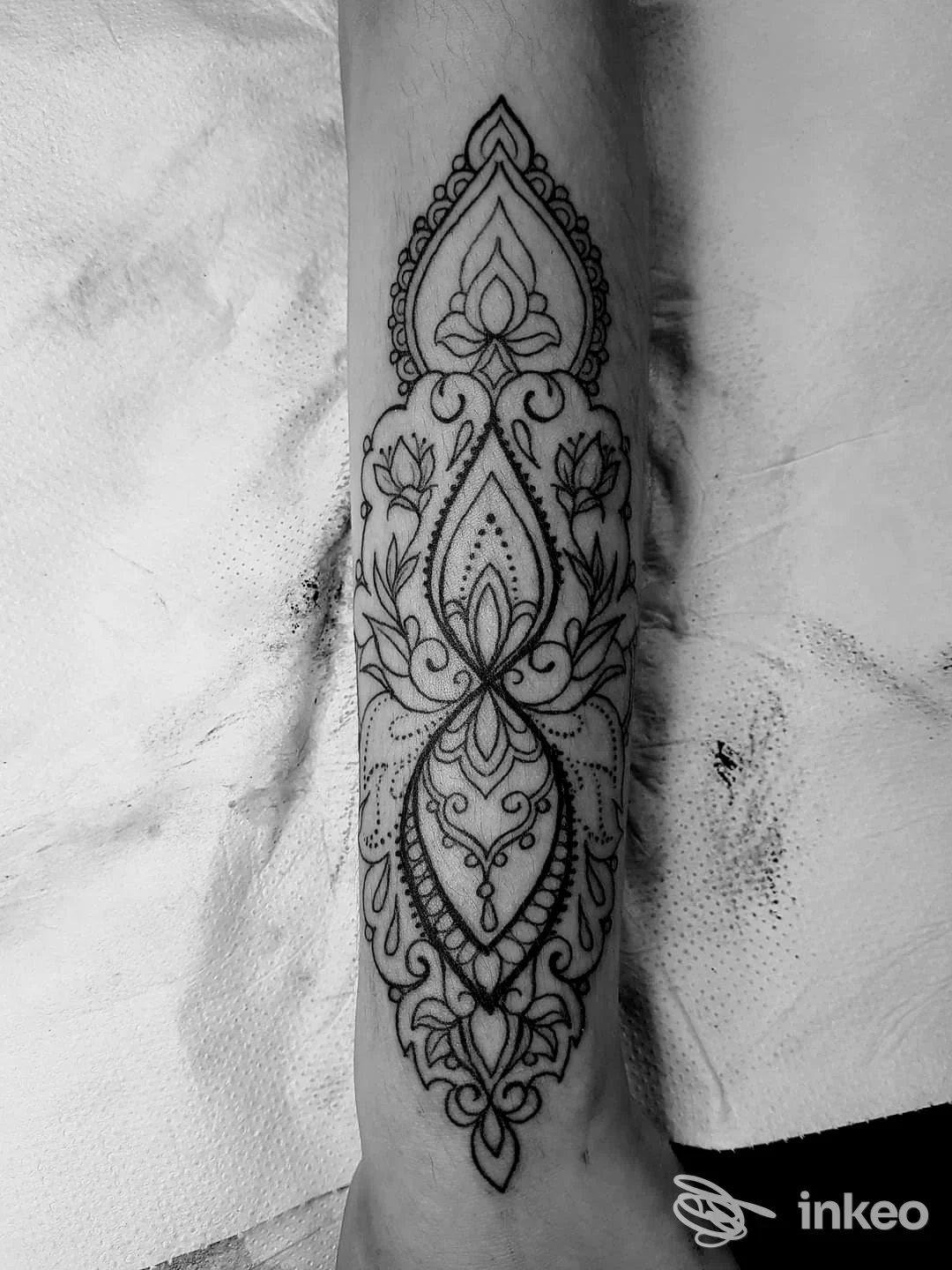 Tatuaggio ornamentale su avambraccio, stile mandala con motivi floreali neri, realizzato sulla pelle.