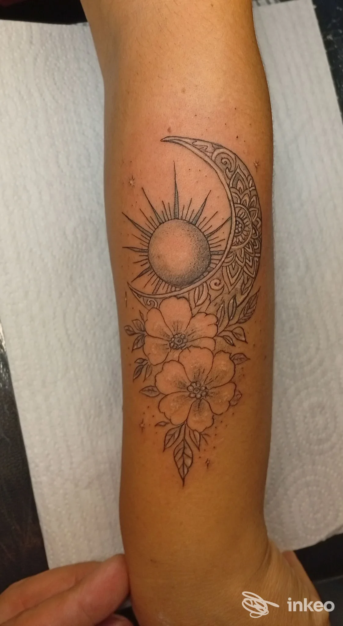 Tattoo visibile sul braccio: sole e luna con motivo ornamentale e fiori, eseguito su pelle. ombre e linee nette; lavoro realizzato nello studio Maya Tattoo & Beauty, a Cosenza.