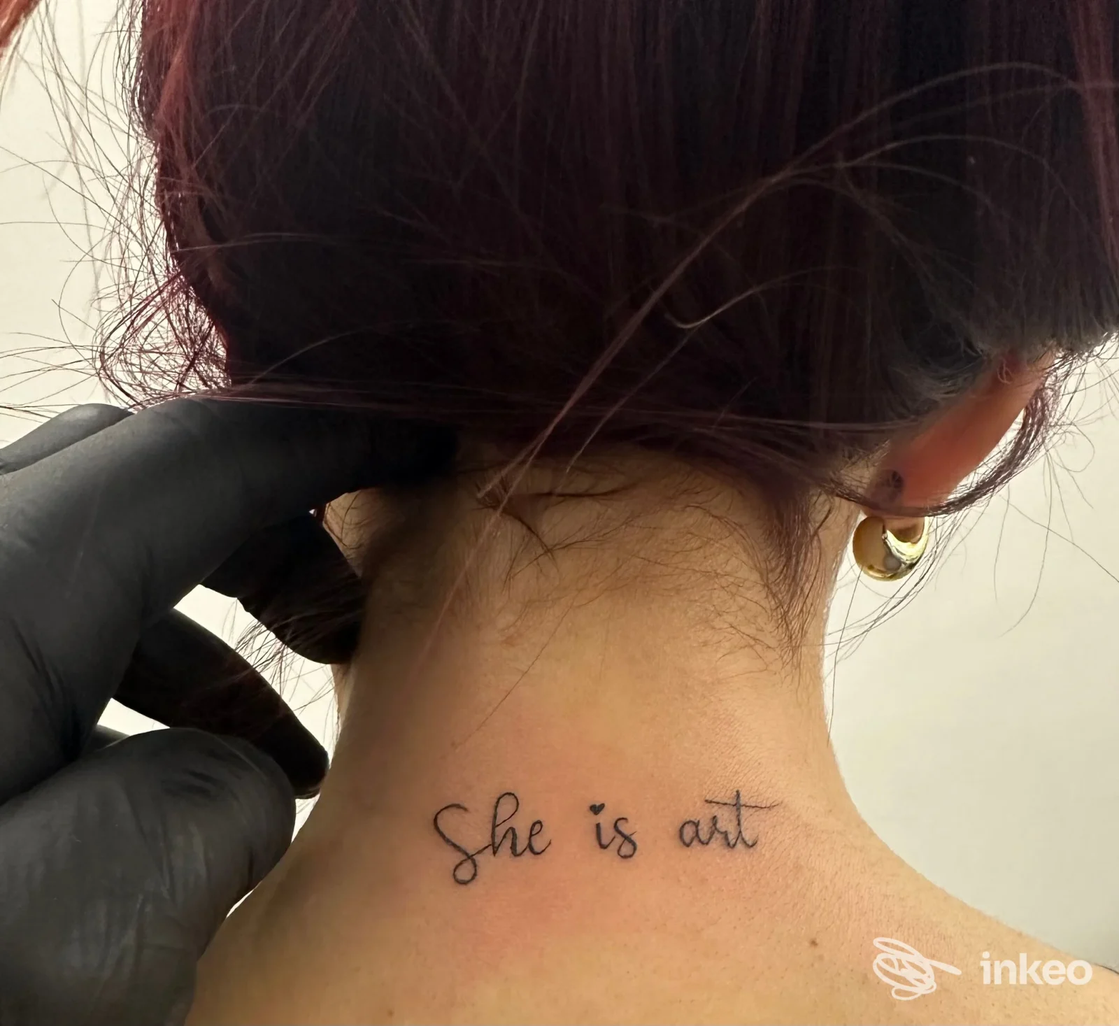 Tattoo sul collo visibile con la scritta «She is art», ritratto sul retro del collo femminile, niente overlay o testo promozionale, studio South Tattoo Studio a Rocca di Neto.