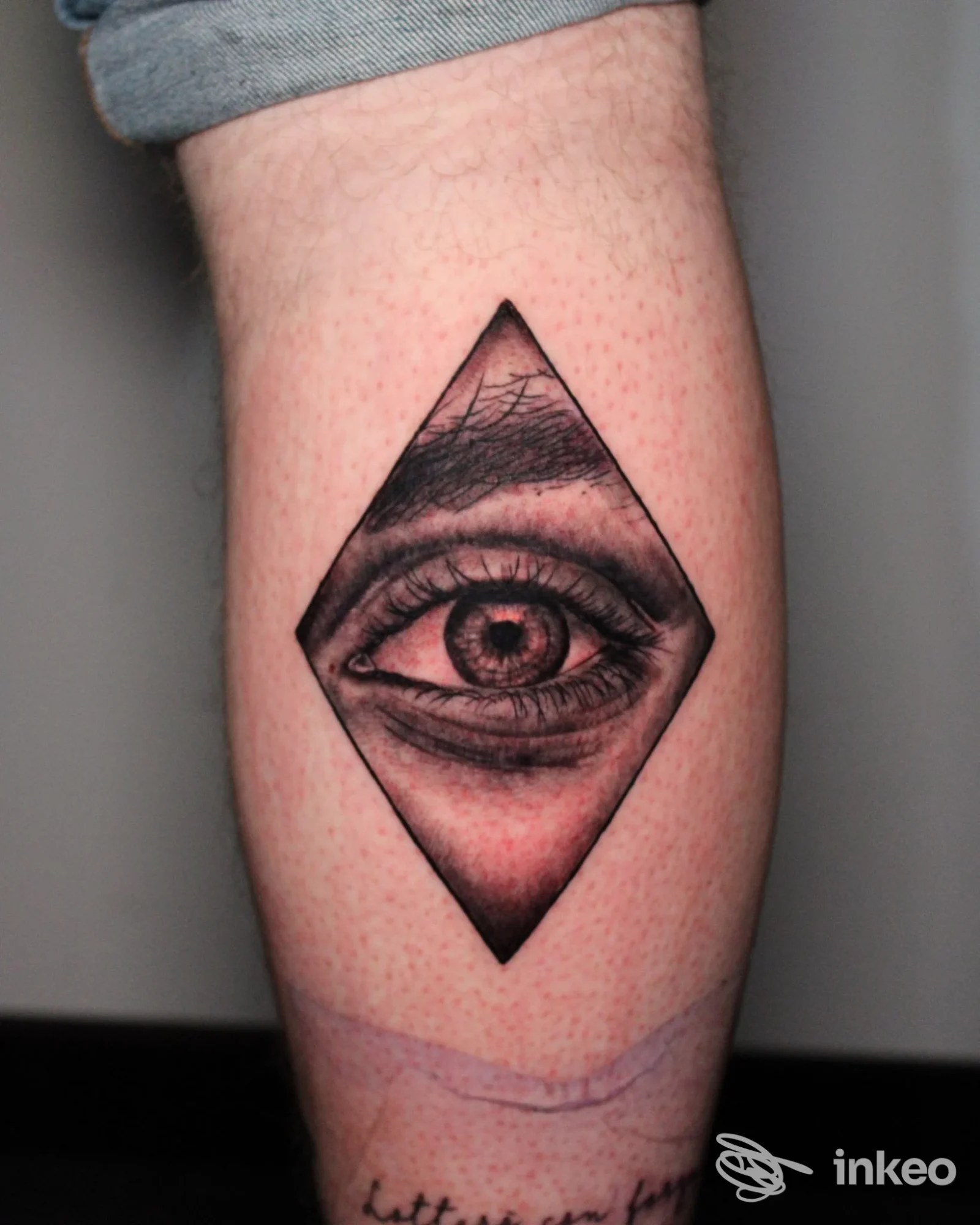 Tattoo sull’avambraccio raffigurante un occhio all’interno di un rombo, realizzazione corporea visibile.