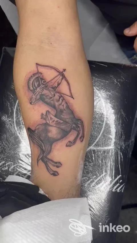 Tatuaggio realistico su avambraccio: cavaliere su cavallo brandisce un arco, realizzato con tonalità nero-grigio, fronte a contrasto marcato e contorni puliti.