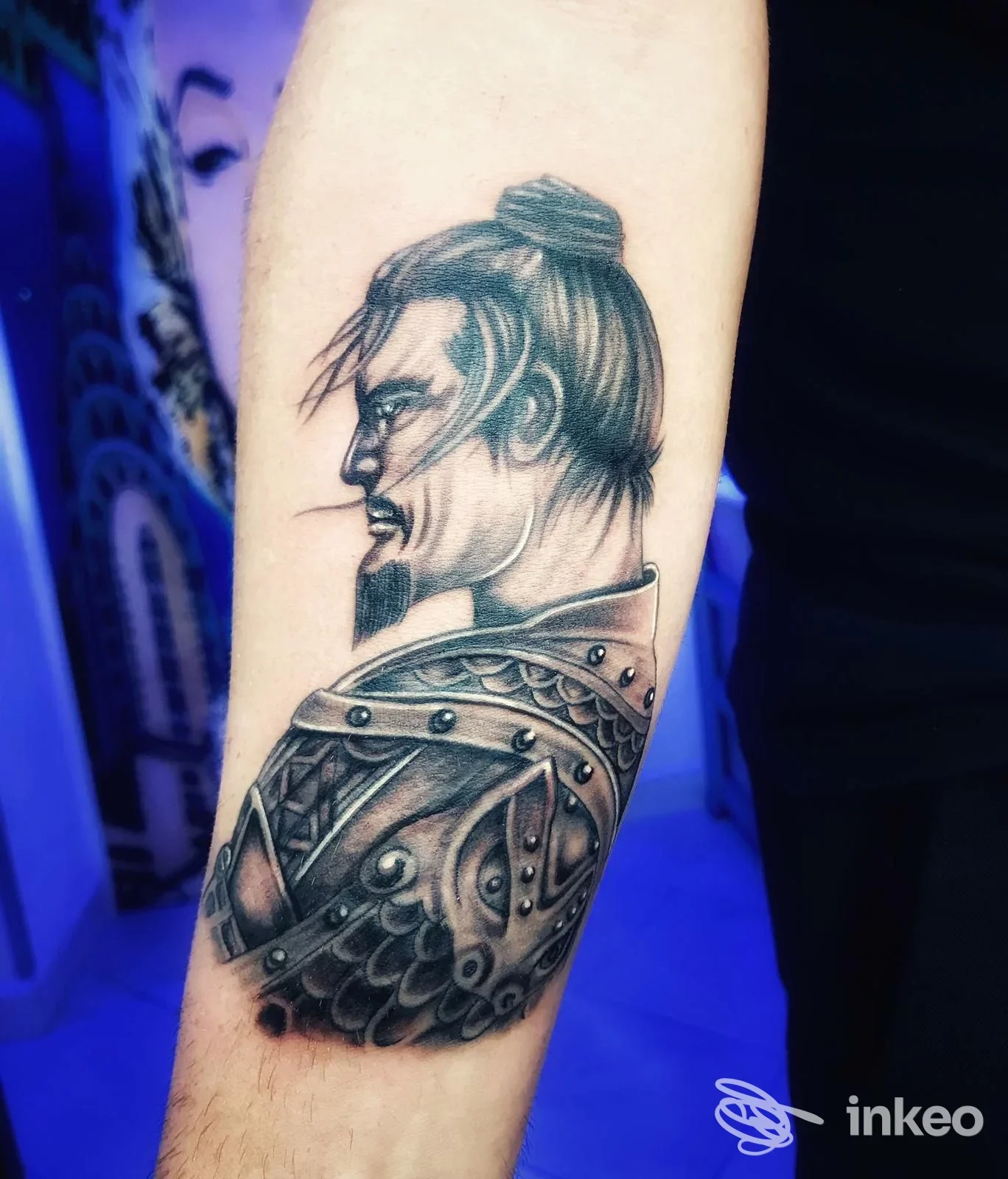 Tattoo visibile su avambraccio: ritratto in stile guerriero con cappuccio, linea e shading nette, realizzato sulla pelle a Giugliano in Campania presso Hollywood Tattoo e Piercing.