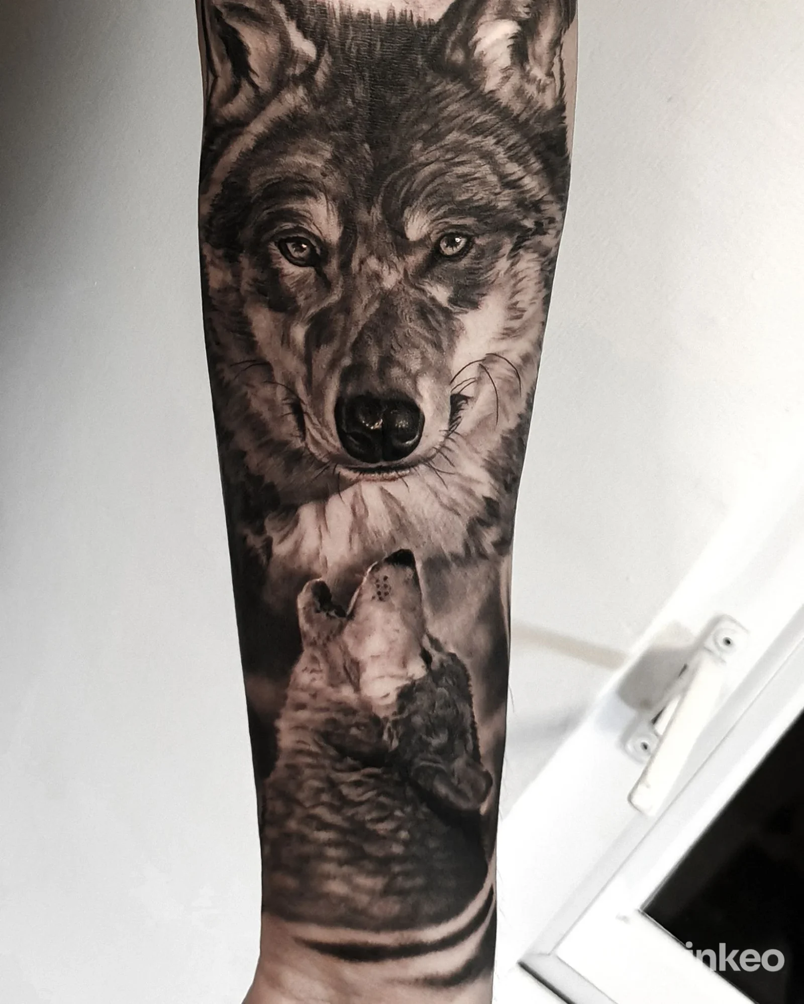 Tatuaggio realistico sull'avambraccio raffigurante due lupi: uno grande che guarda avanti e un dettaglio minore, realizzato interamente sulla pelle.
