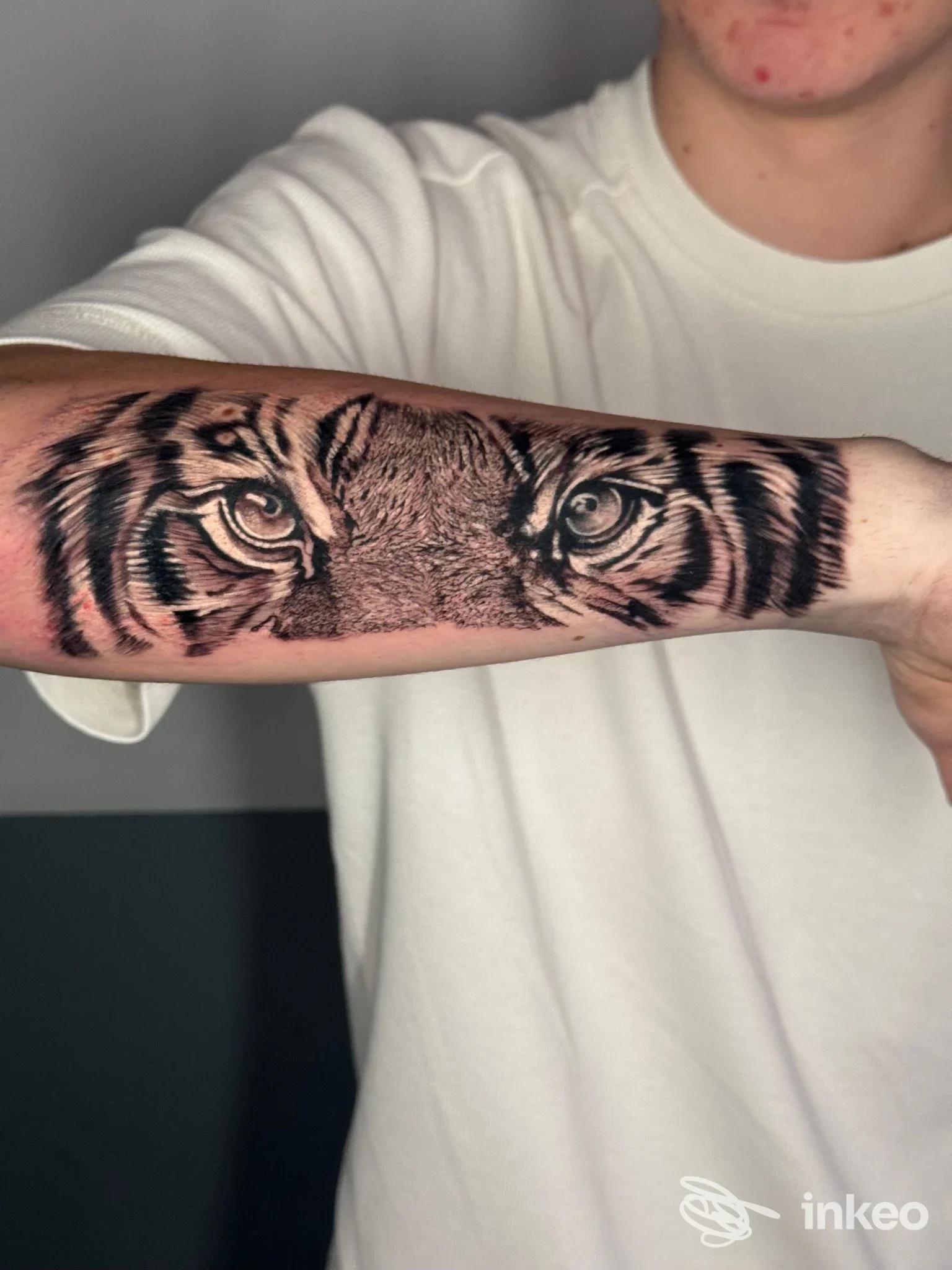 Tattoo realistico di tigre sull'avambraccio di un uomo, in bianco e nero, con dettagli a tratto fine e sfumature, visibile su pelle reale.