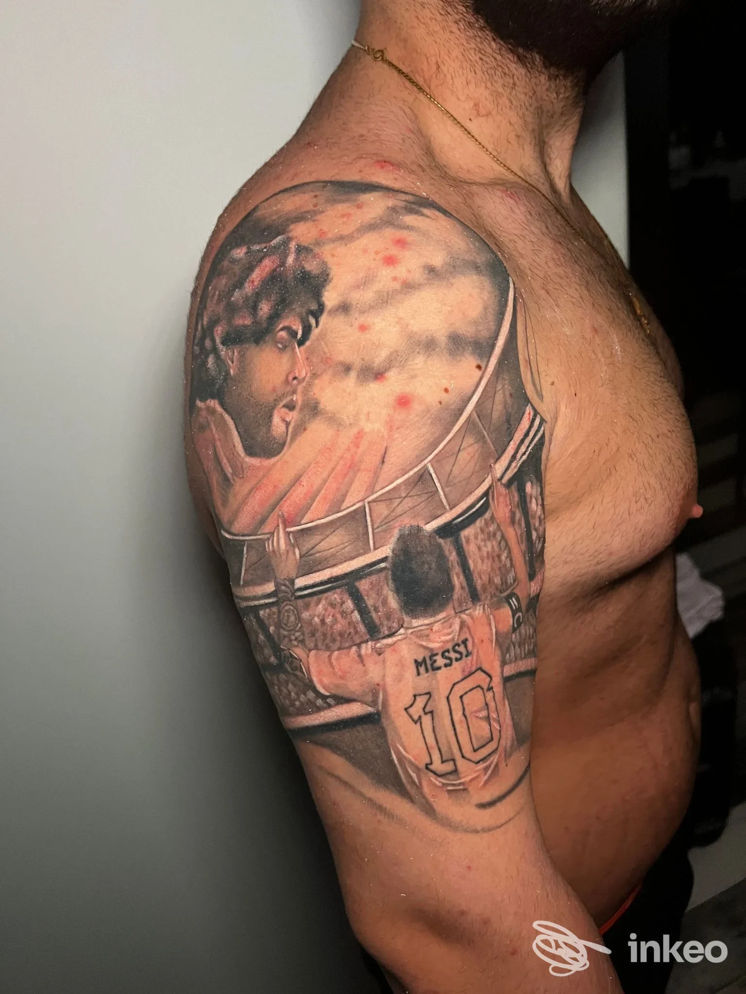 Tattoo realistico su braccio sinistro: ritratto di uomo e dettagli scenografici, braccio e spalla ben visibili.