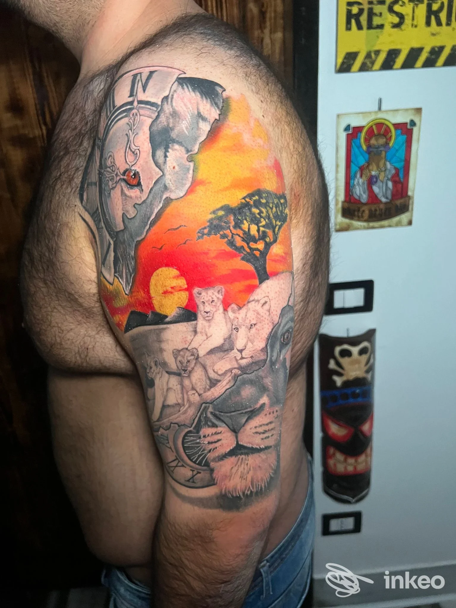 Tattoo a braccio visibile: scene colorate con paesaggio al tramonto, figure e animali su una pelle maschile, in un contesto di studio a Napoli.