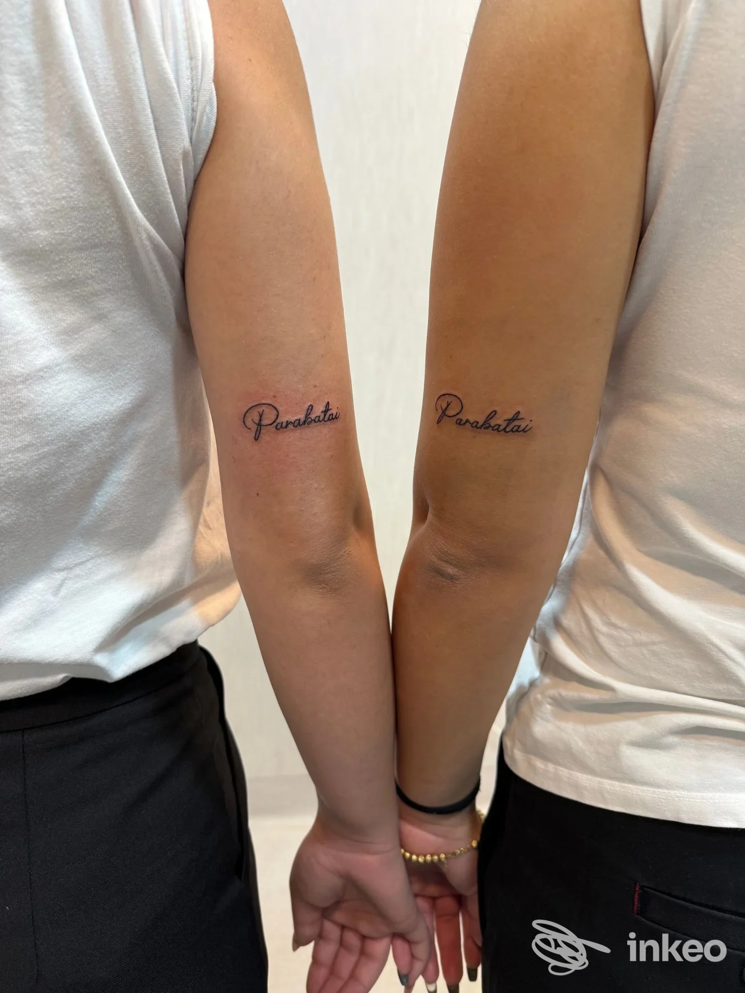 Due tatuaggi identici sull interno dei due avambracci, in stile scrittura script, tatuati sulla pelle con colore scuro, indossano magliette bianche, nello studio Cask Tattoo a Portici.