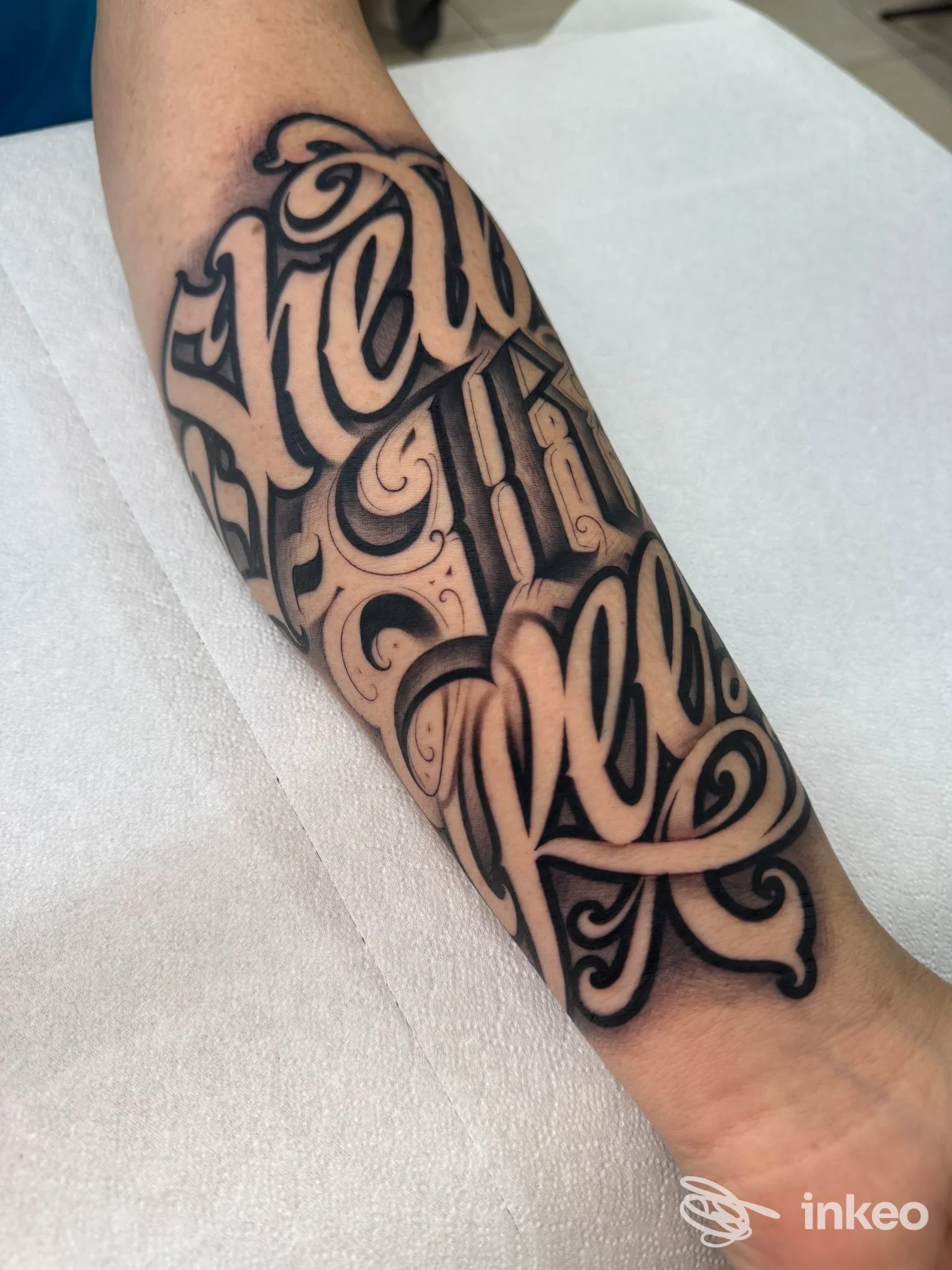 Avambraccio di una persona con tatuaggio a lettering e motivi ornamentali in stile décor, eseguito nello studio Family Addiction Tattoo Shop a Giugliano in Campania.