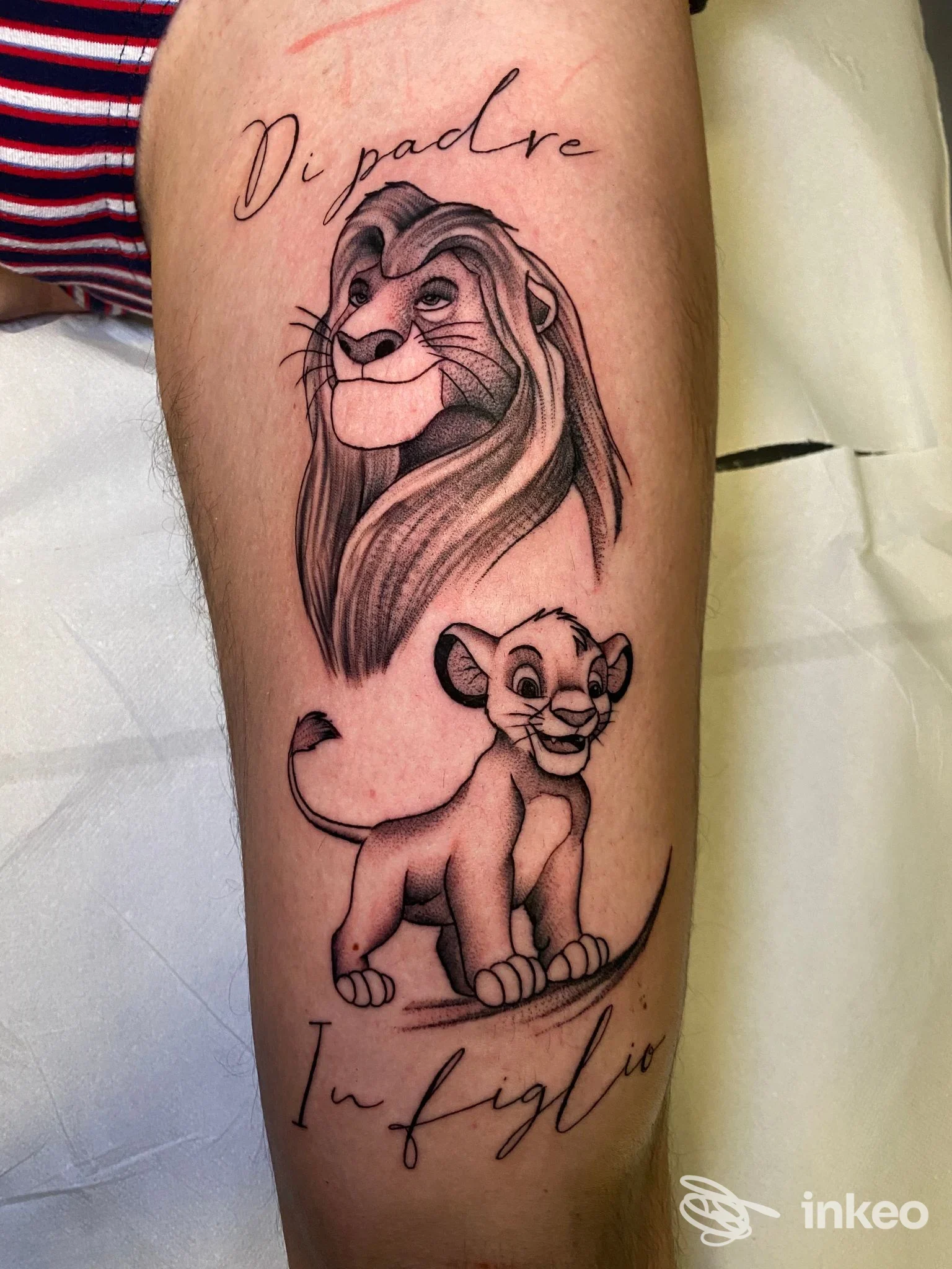 Tattoo su polpaccio raffigurante leone adulto e leoncino con testo in corsivo, immagine nitida su pelle reale, senza watermark o overlay.