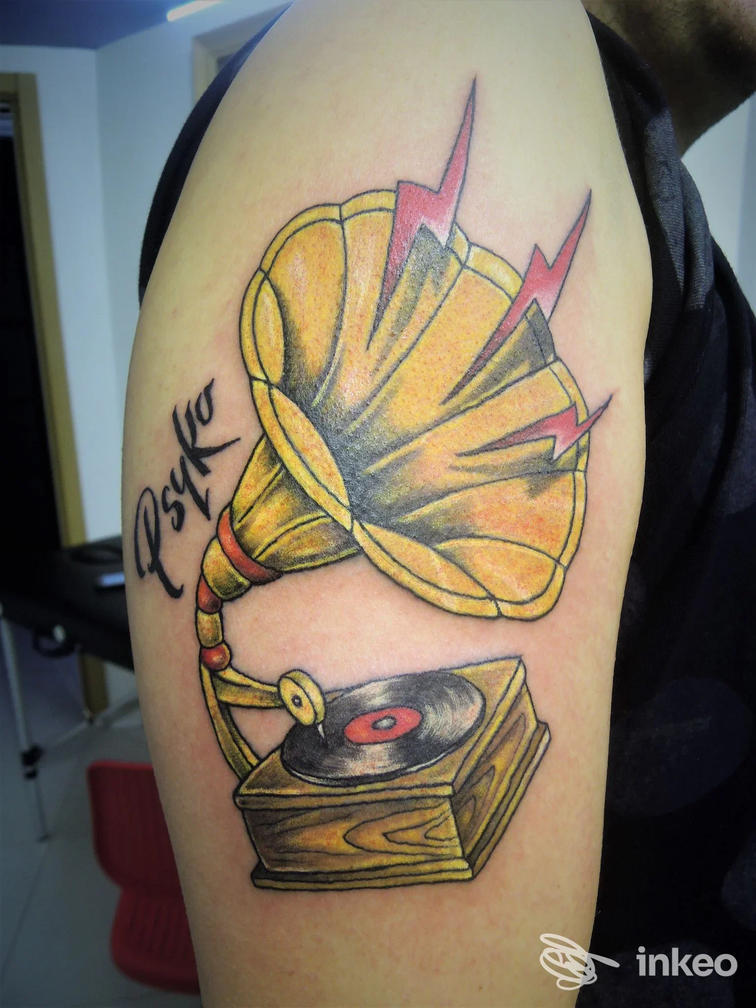 Tattoo su braccio raffigurante un grammofono con altoparlante dorato, con dettagli grafici colorati, realizzato da TatuArti Studio InkMaster a Caivano