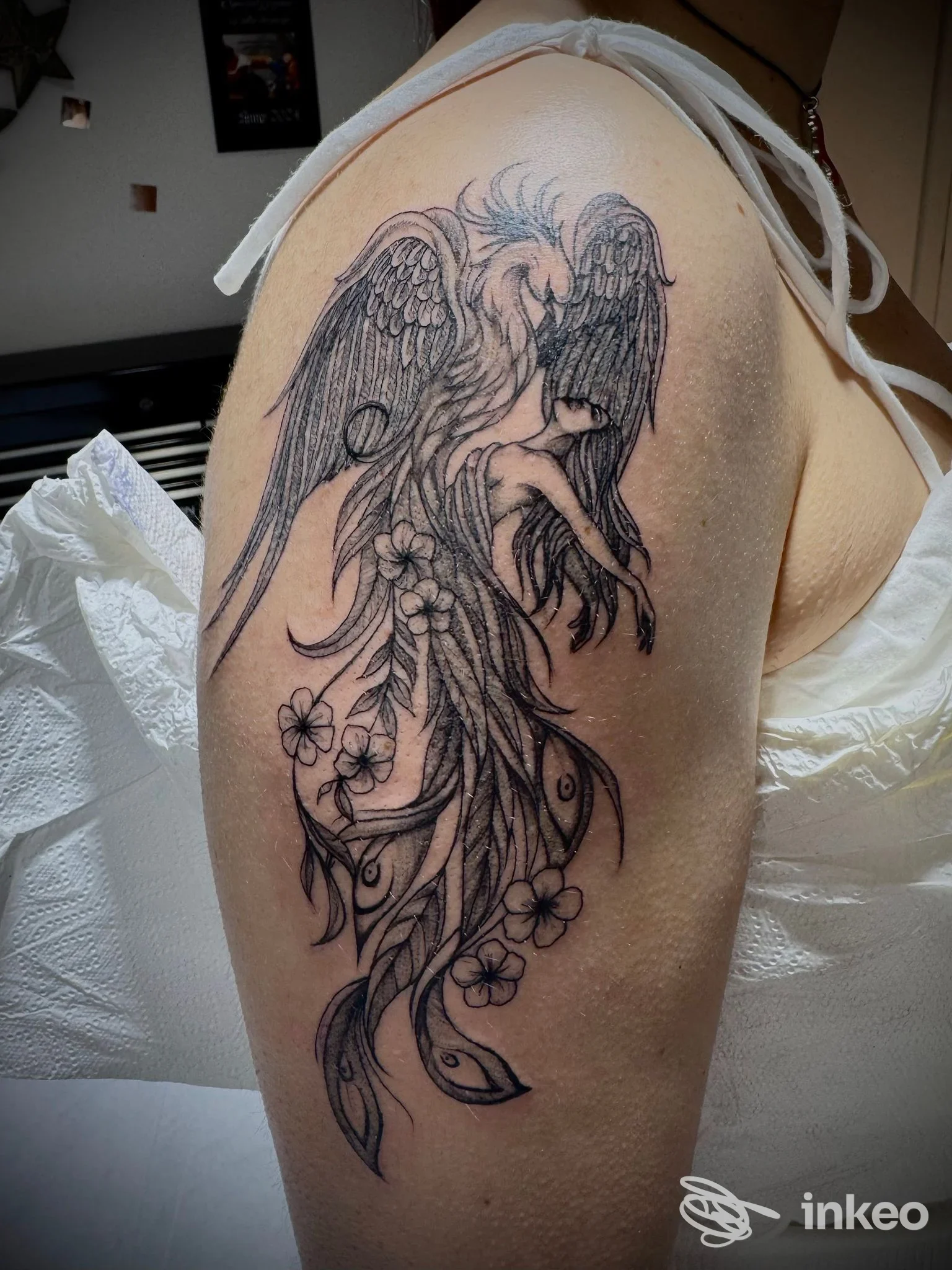 Tatuaggio raffigurante un angelo con ali stilizzate sul braccio, in bianco e nero, eseguito su pelle.