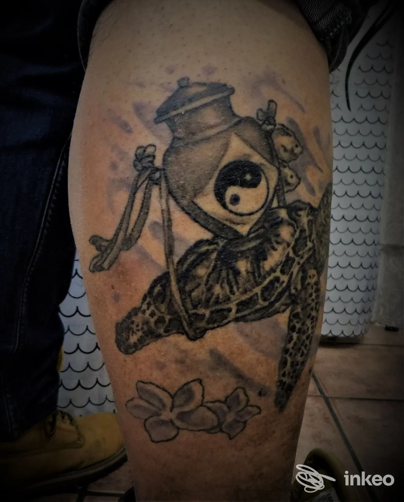 Tattoo su gamba raffigurante una creatura simile a tartaruga con elementi decorativi; tonalità scure su pelle, nessun volto visibile, nessun overlay di rete.