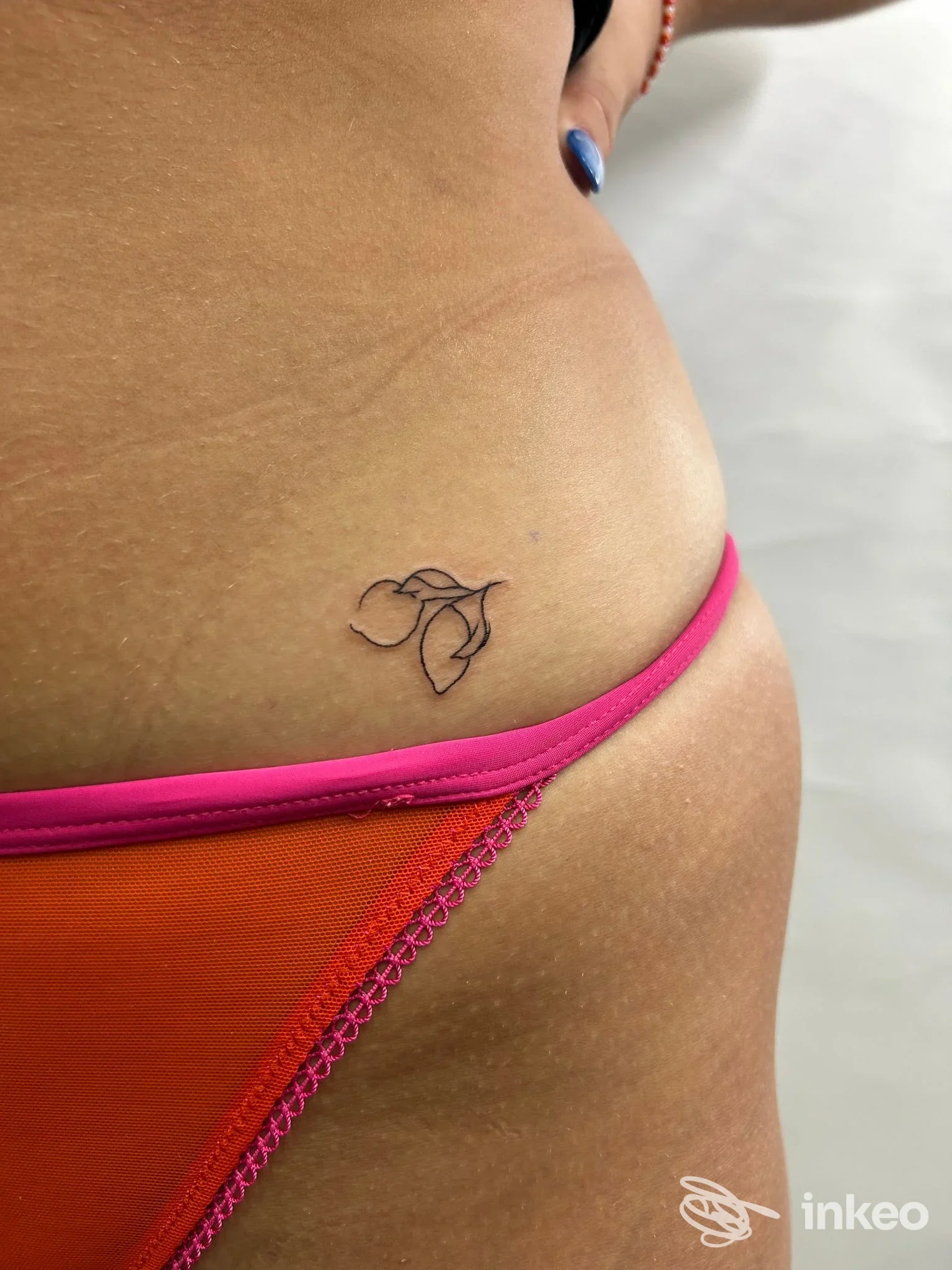 Piccolo tatuaggio a linee astratte sulla pelle del fianco, vicino all’anca, visibile con bikini rosa, eseguito in Napoli presso ManoSanta tattoo shop.