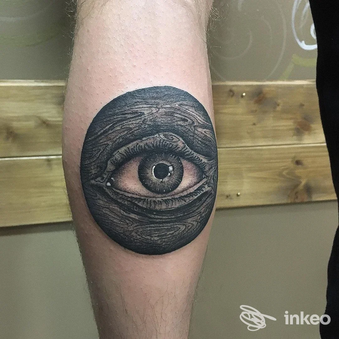 Tattoo occhio realistico in tondo scuro sull’avambraccio, esecuzione in tonalità grigie con dettagli fini, visibile come realizzazione corporea.