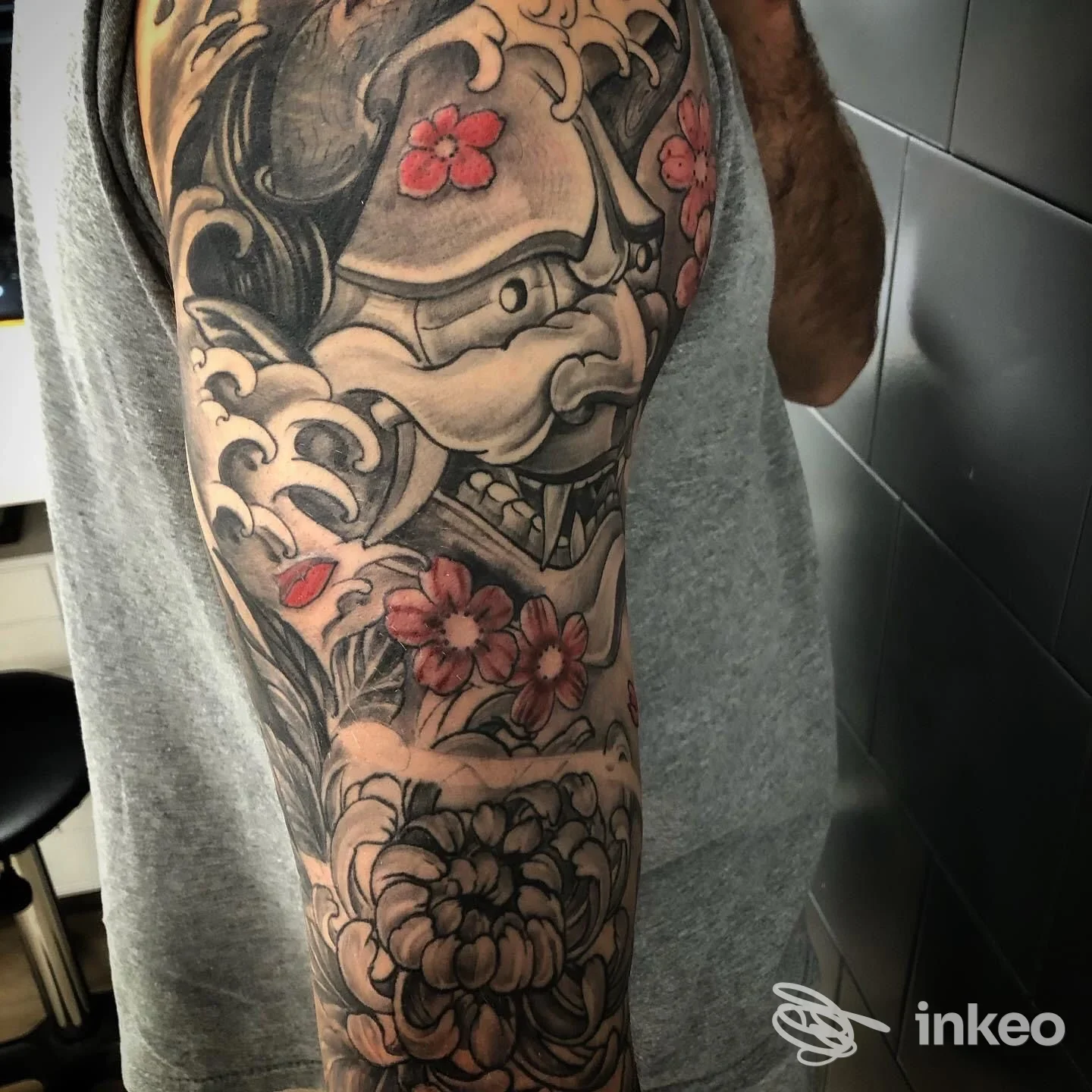 Braccio di persona con tatto a maniche lunghe: animali stilizzati in bianco e nero con fiori rossi, tattoo integrale visibile lungo braccio.