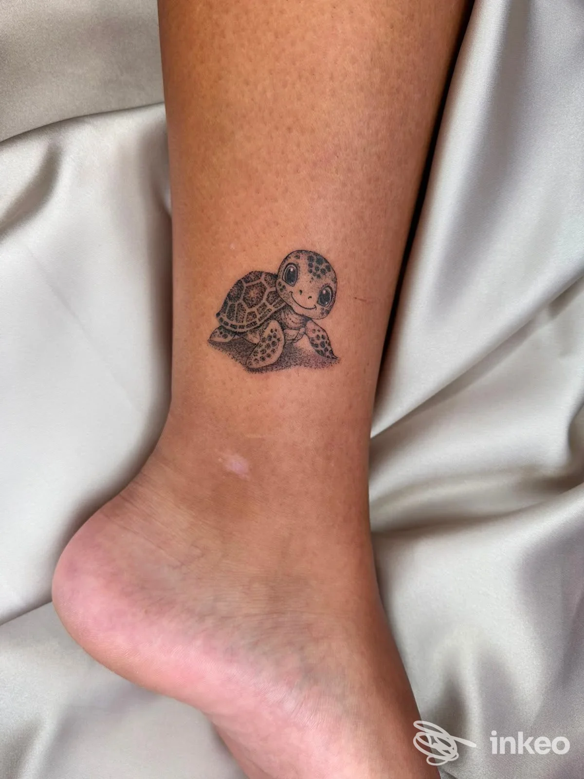 Tattoo piccola di una tartaruga stilizzata sulla caviglia, realizzata sulla pelle nuda, senza persone visibili o elementi di social media.