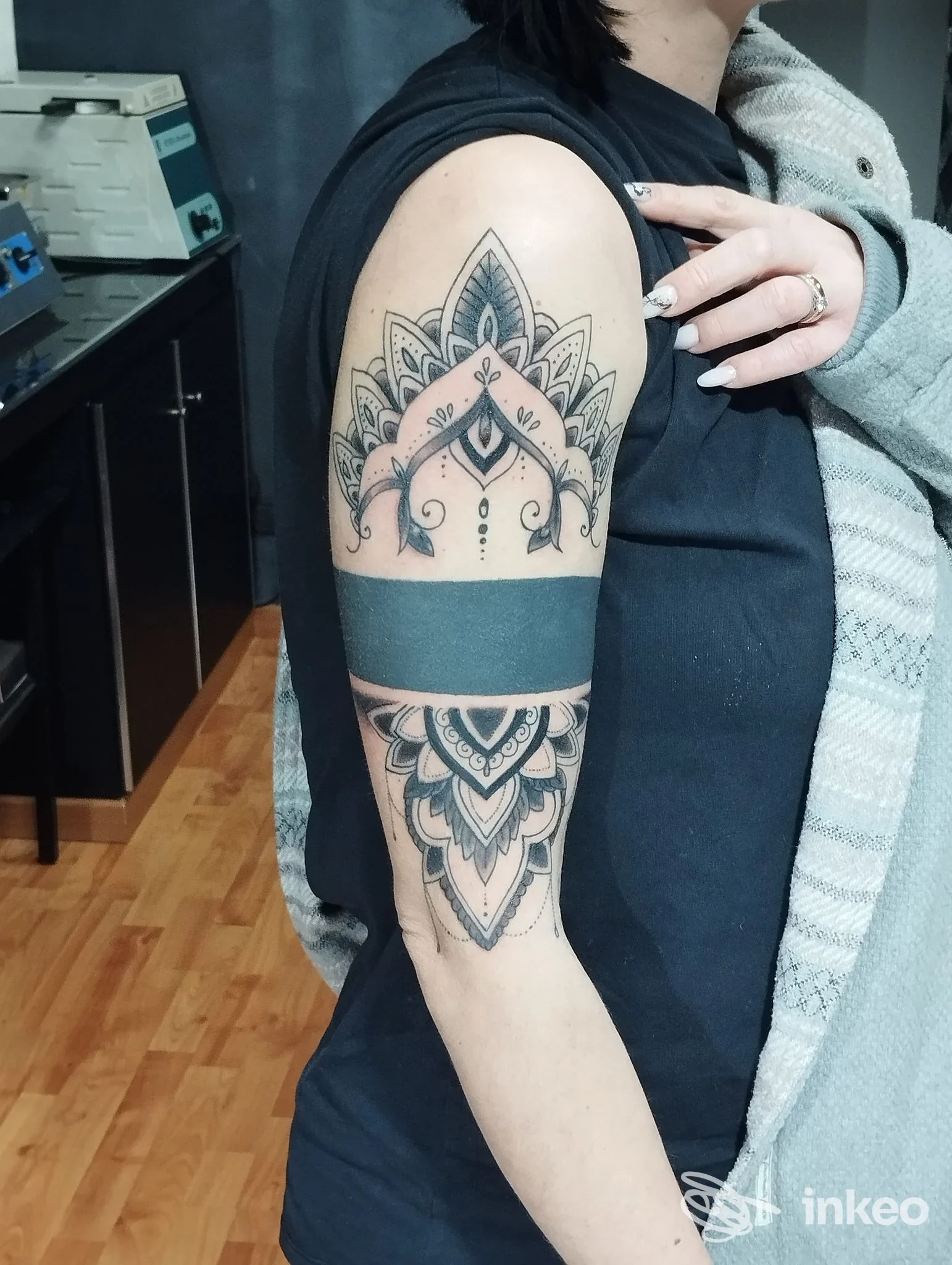 Parte superiore del braccio sinistro visibile con tatto geometrico in stile mandala, tatuaggio completo e ben definito sulla pelle.