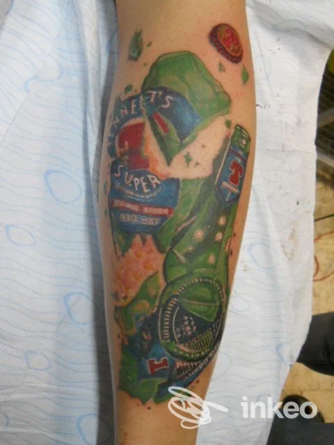 Tatuaggio realistico su braccio raffigurante una bottiglia di bevanda verde con disegno cromato, visibile su pelle umana, studio Non Solo Tattoo Caserta.
